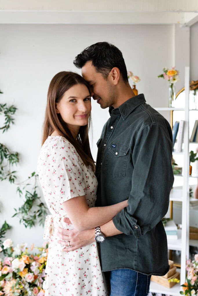 A husband holds his wife close as she looks at the camera. 