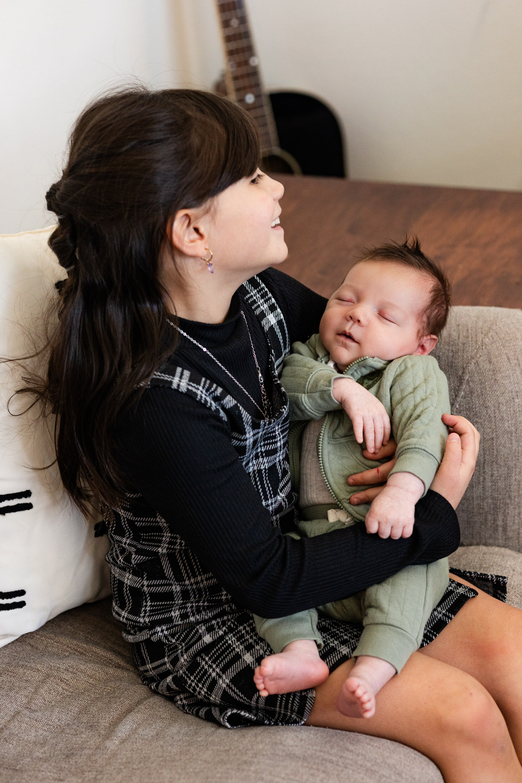 Older sister holds newborn baby brother and smiles.