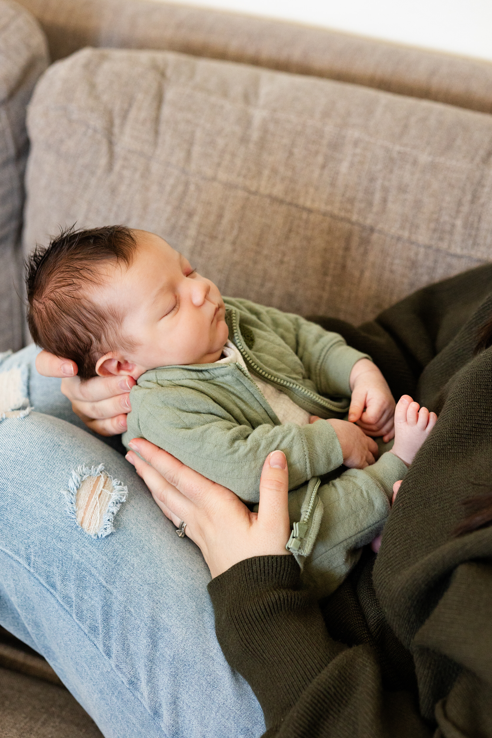 Newborn baby sleeps in his mom's arms.