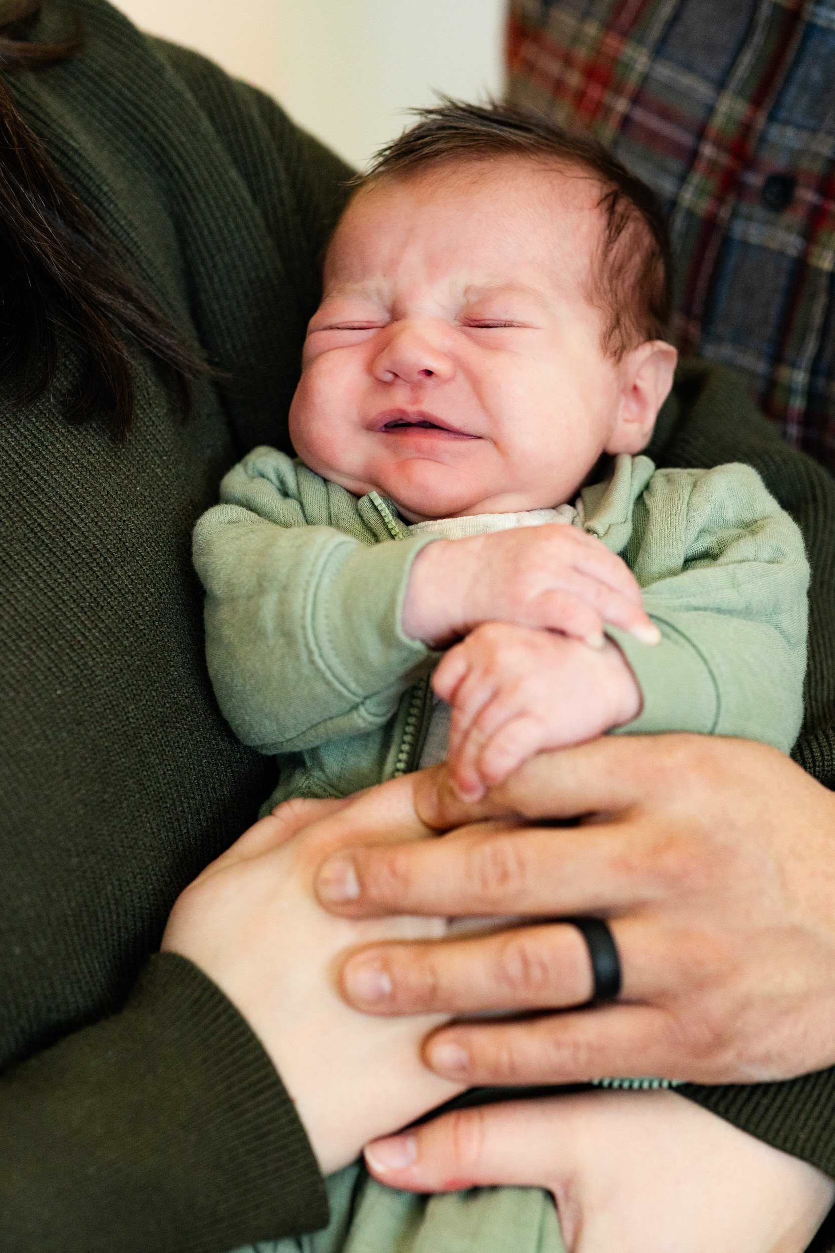 Newborn baby boy is held between mom and dad.
