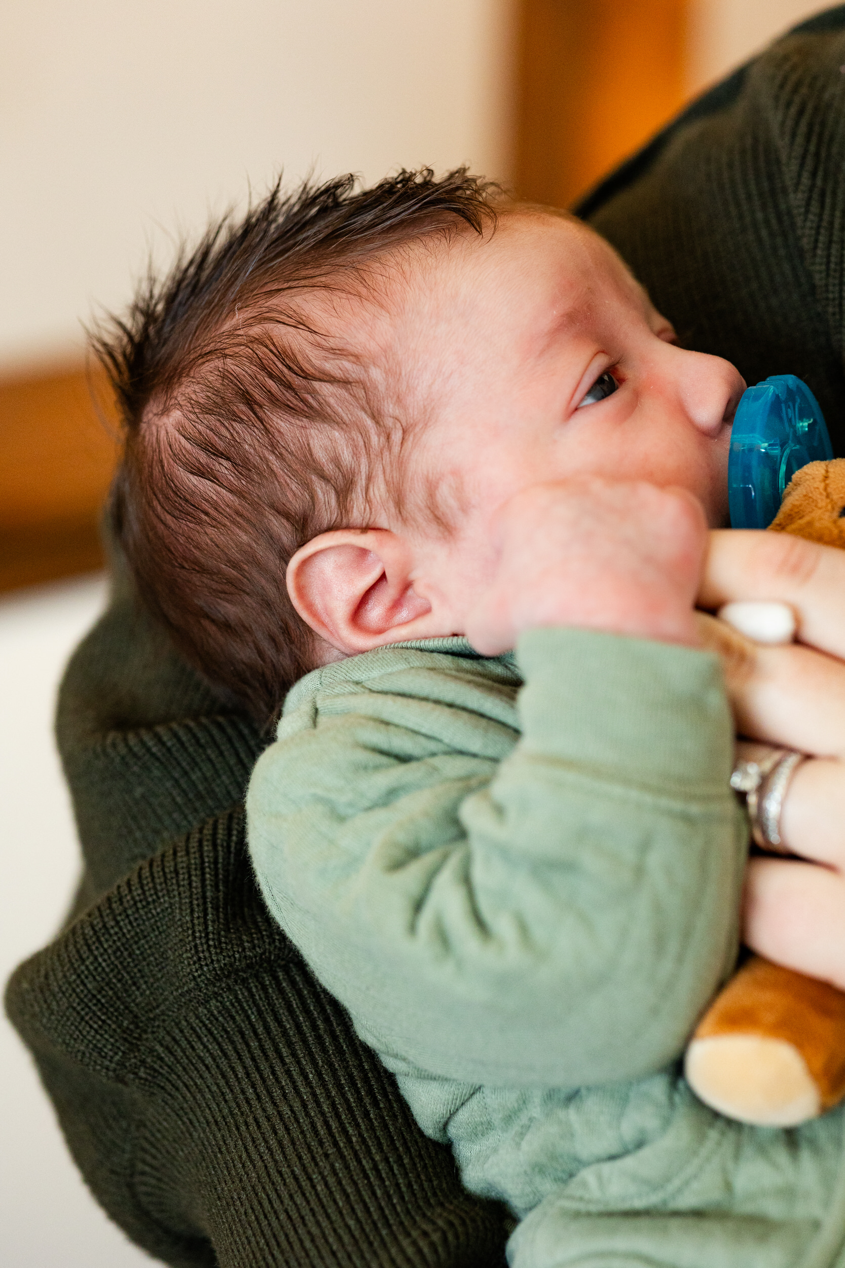Newborn baby boy holds onto mom's finger.