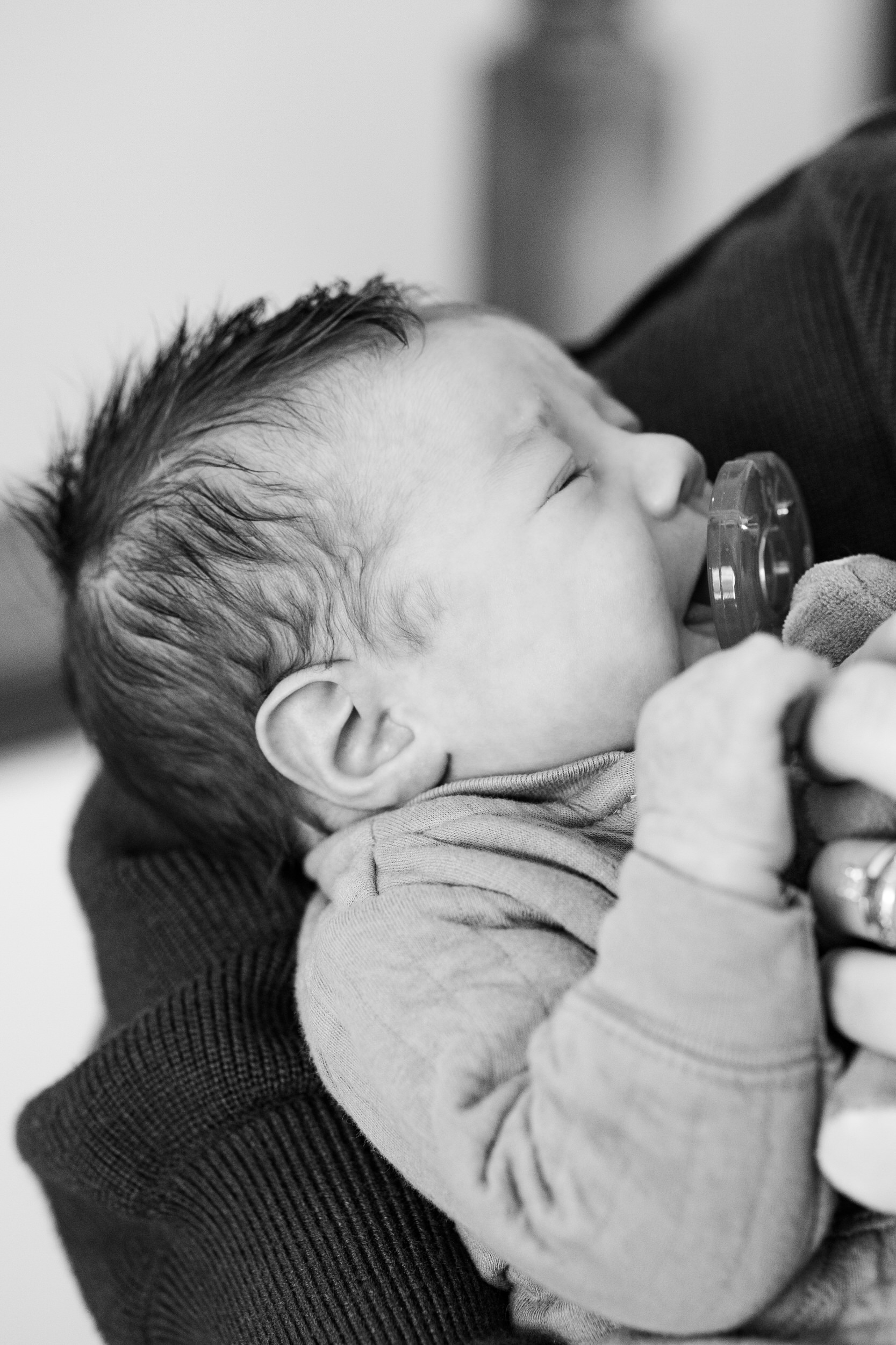 Newborn baby boy cries in his mom's arms.