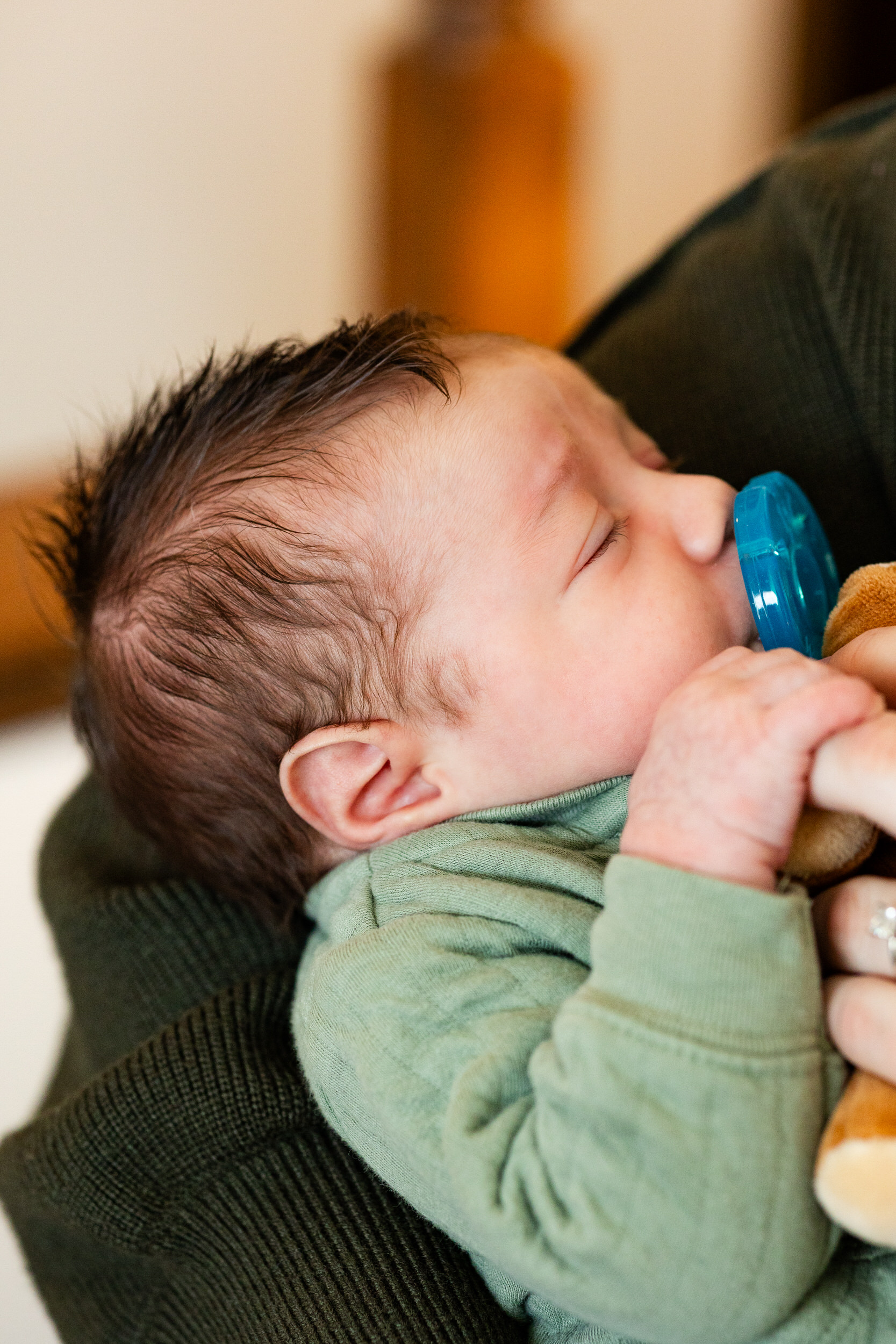 Newborn baby boy sleeps in his mom's arms.
