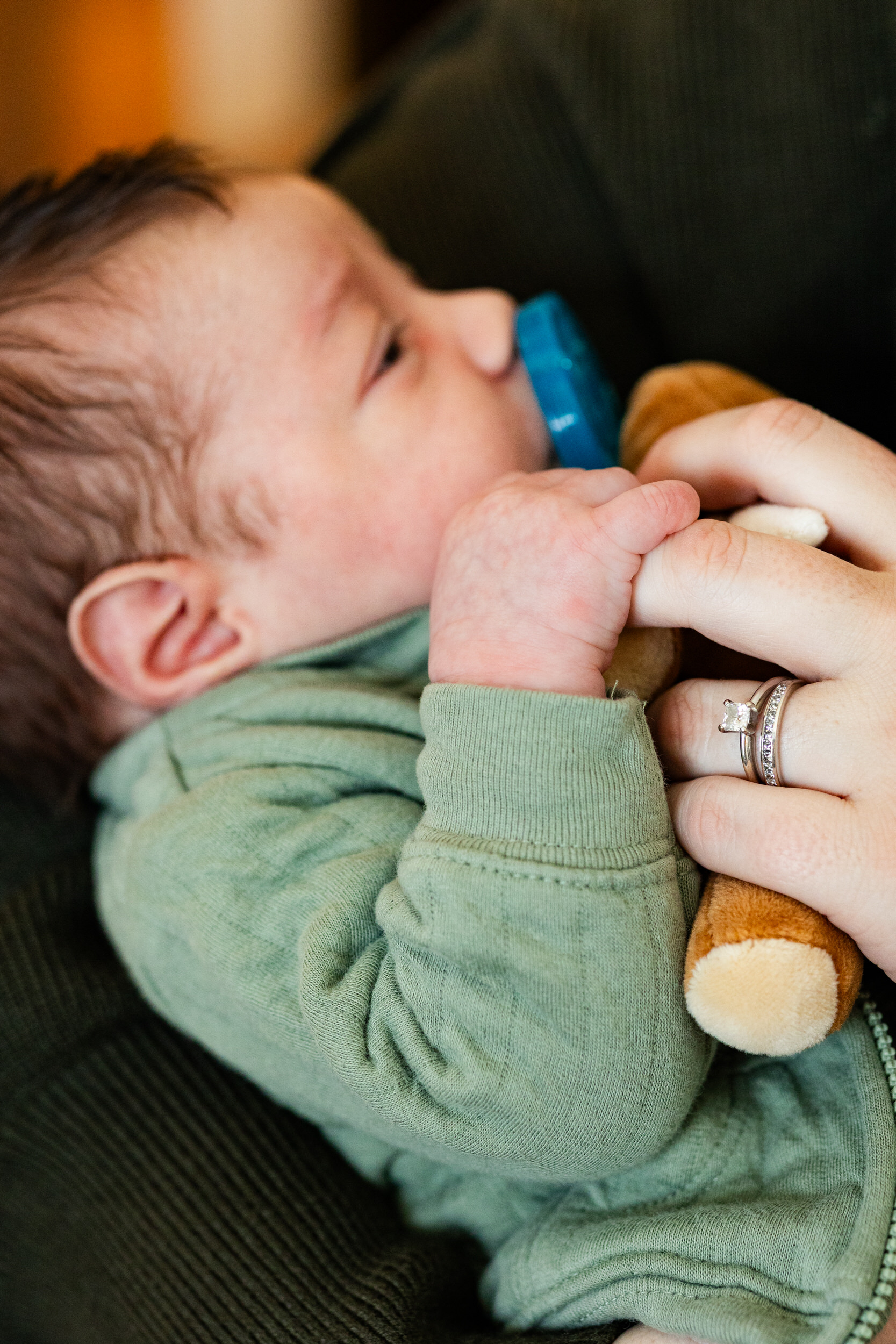 Newborn baby boy holds onto his mom's finger.