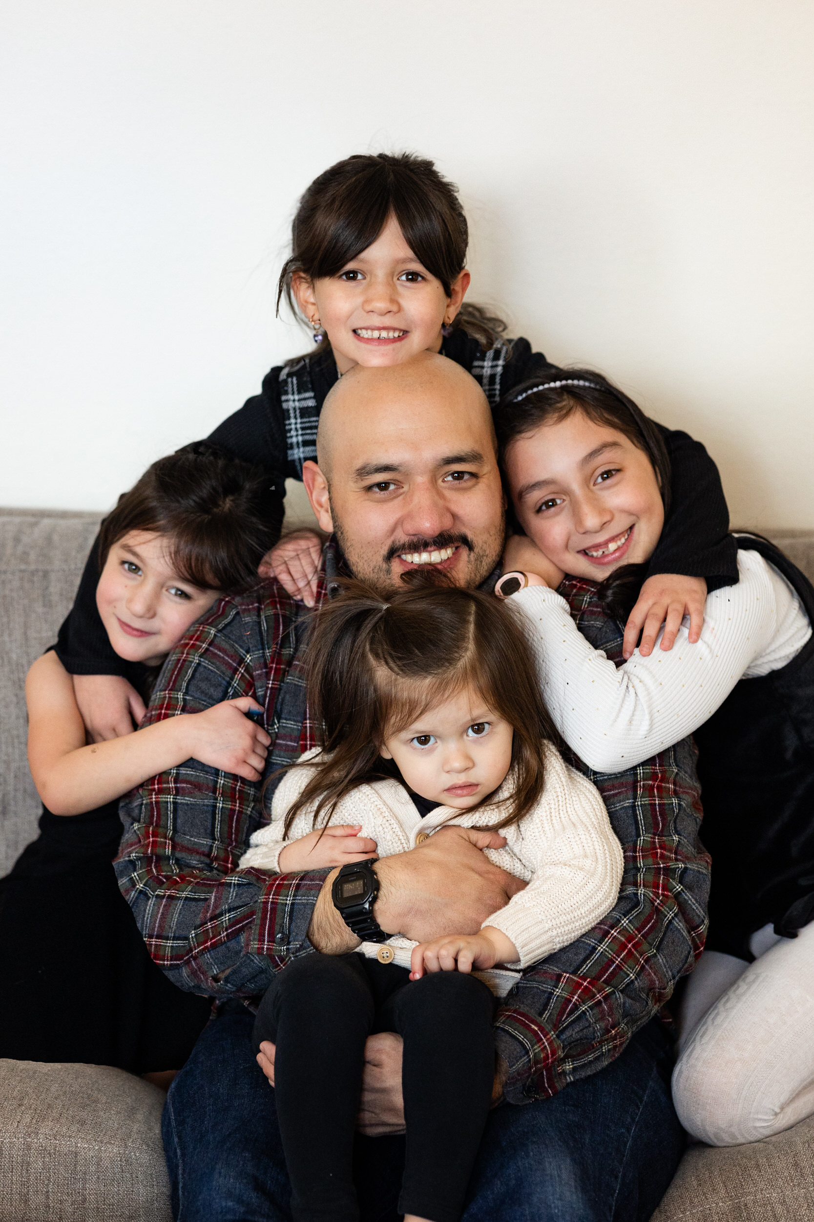 A dad is surrounded by his four young daughters.