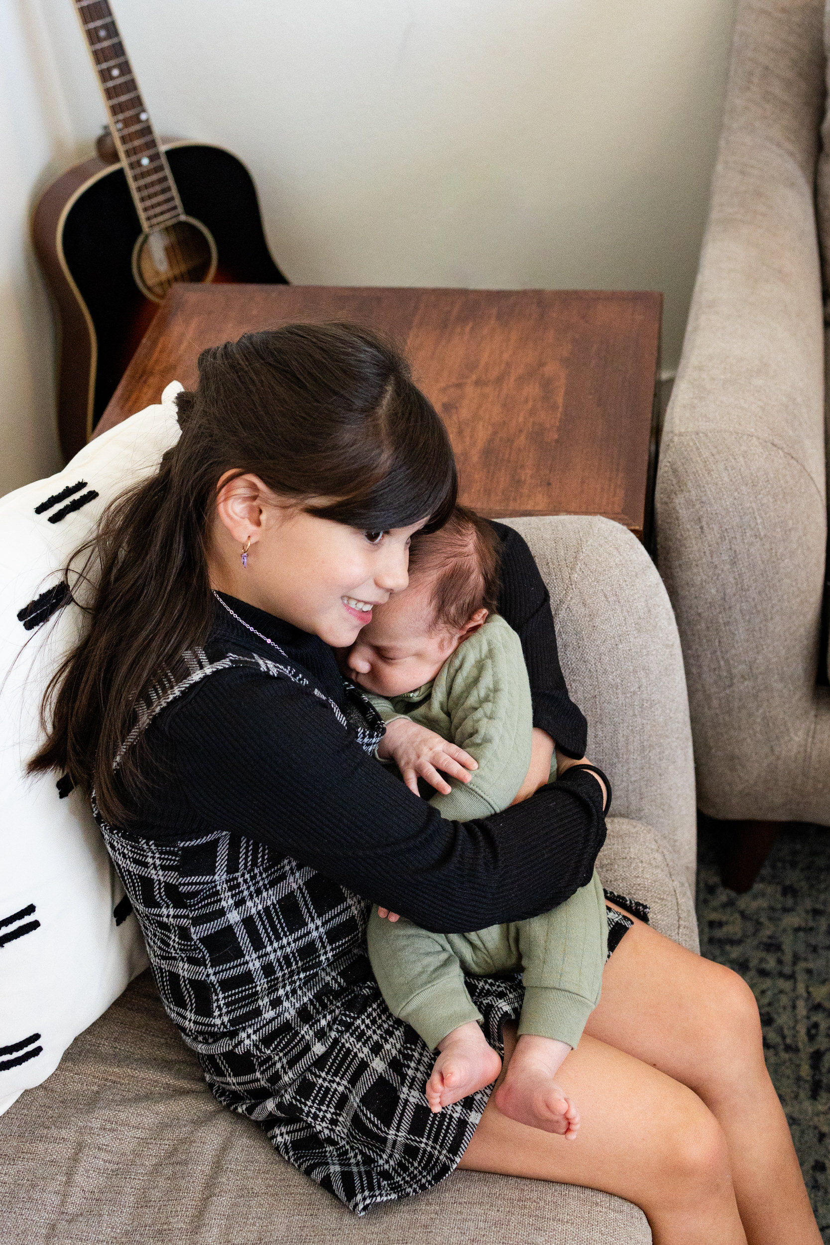 An older sister snuggles her newborn baby brother.