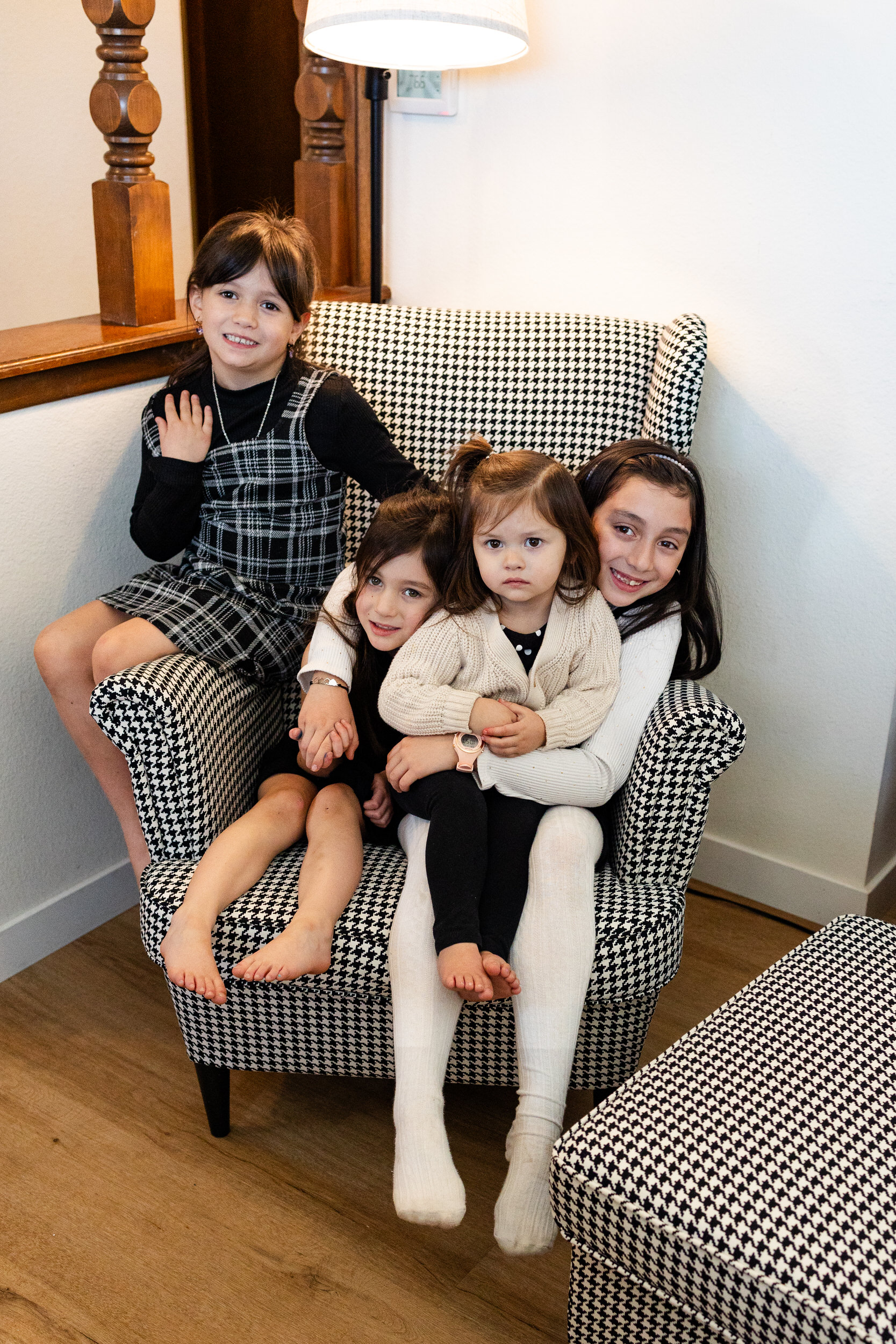 Four young sisters sit on a chair together.