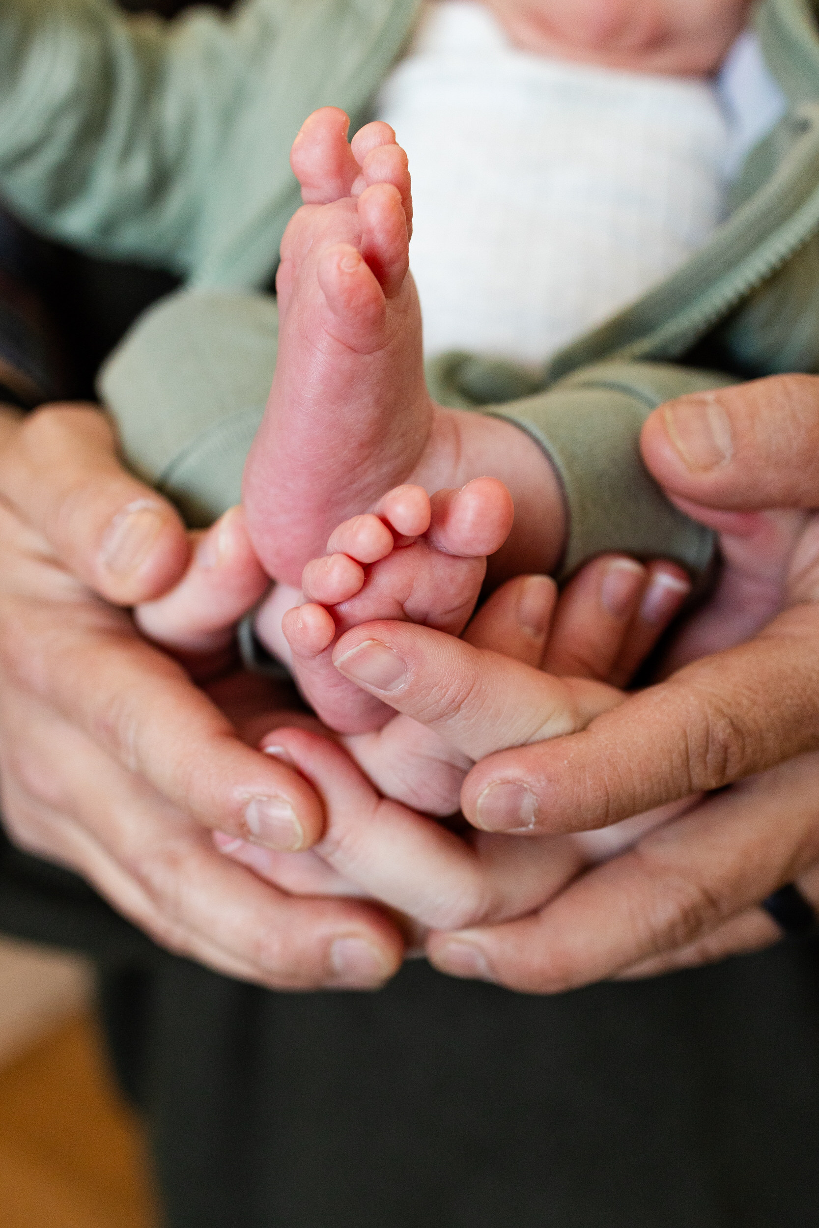 Newborn baby feet being held by mom and dad's hands.