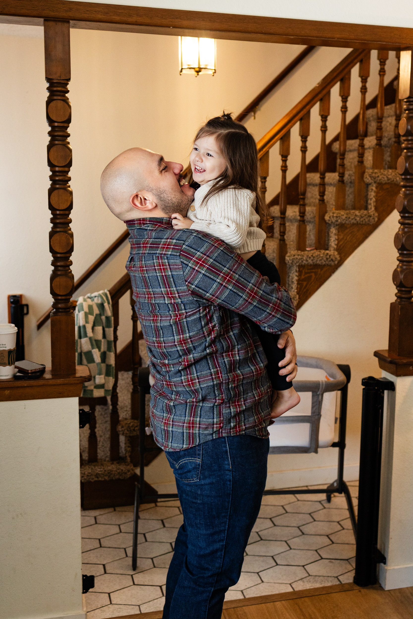 A dad holds his young daughter and laughs with her.