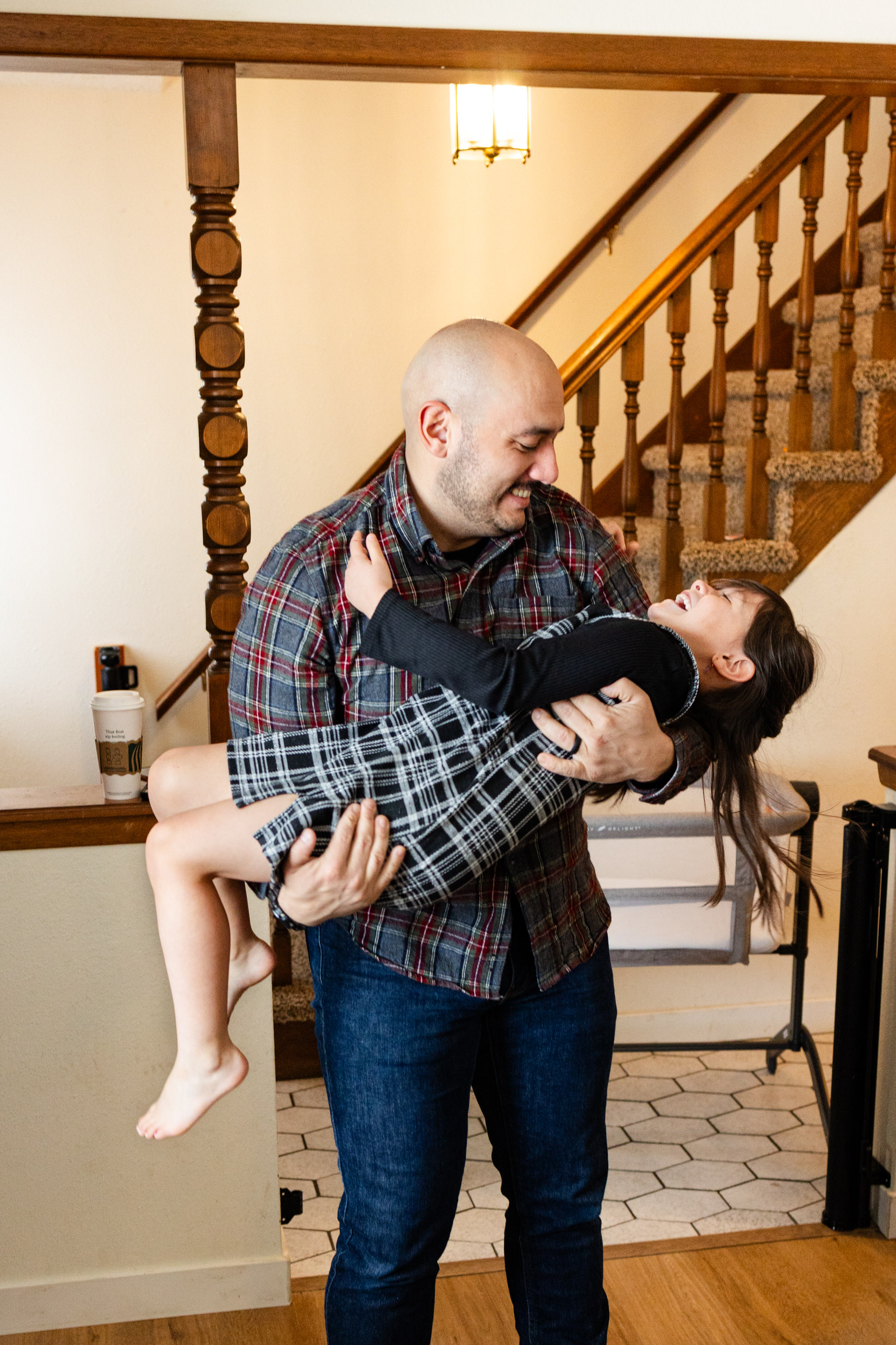 A dad holds his young daughter and laughs with her.