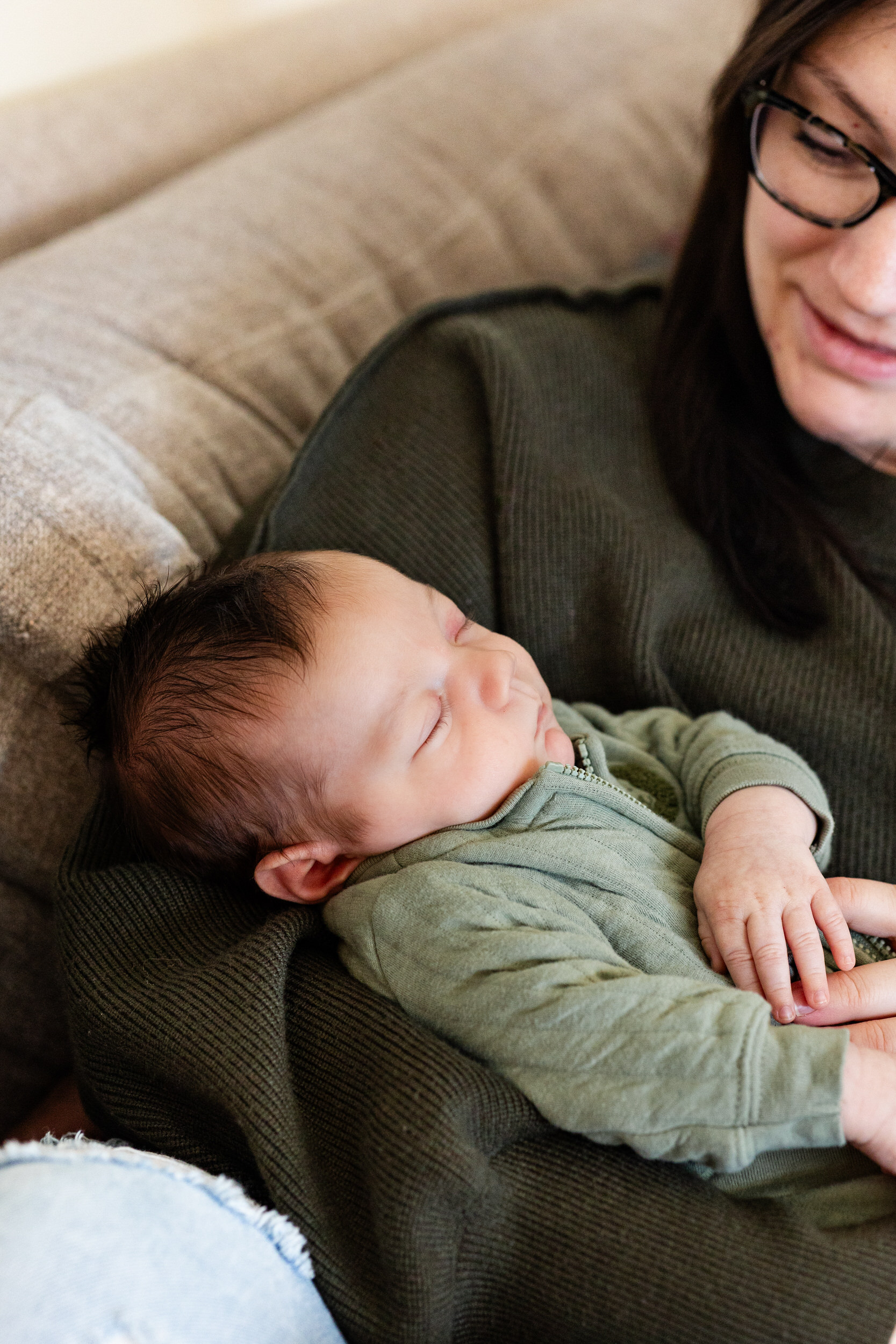 Newborn baby boy sleeps in his mom's arms.