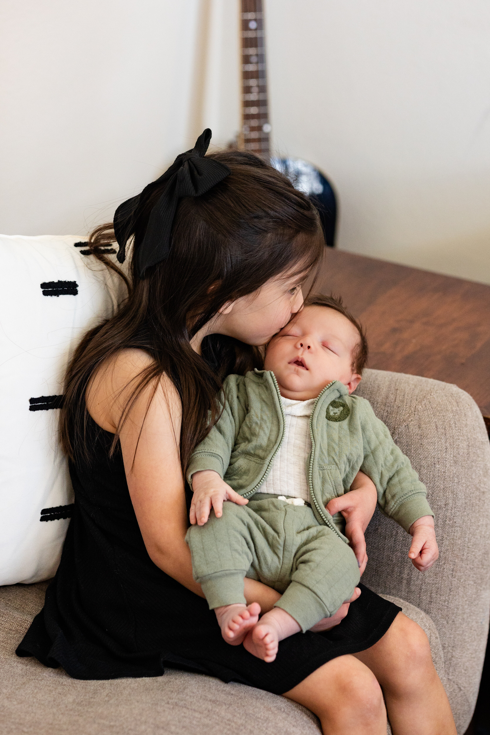 Older sister kisses newborn baby brother.
