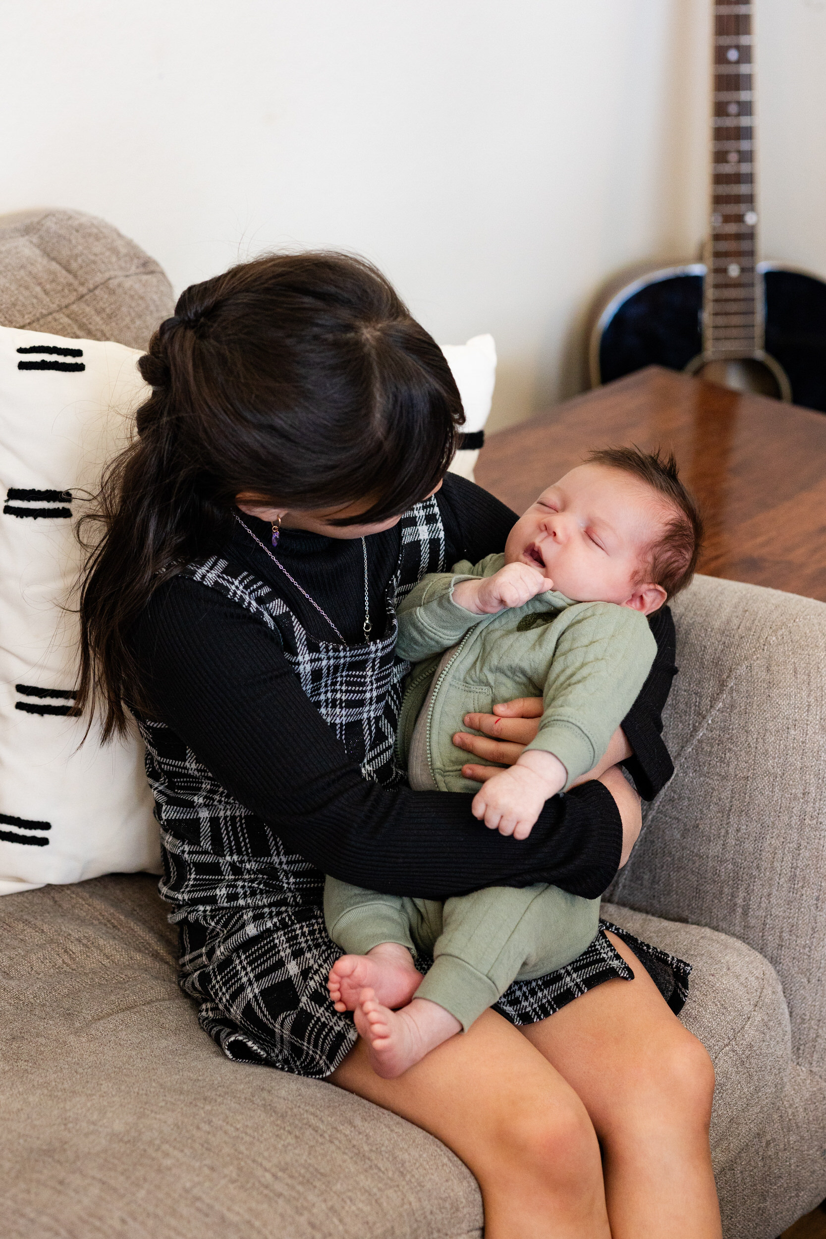 Older sister holds and looks at newborn baby brother.