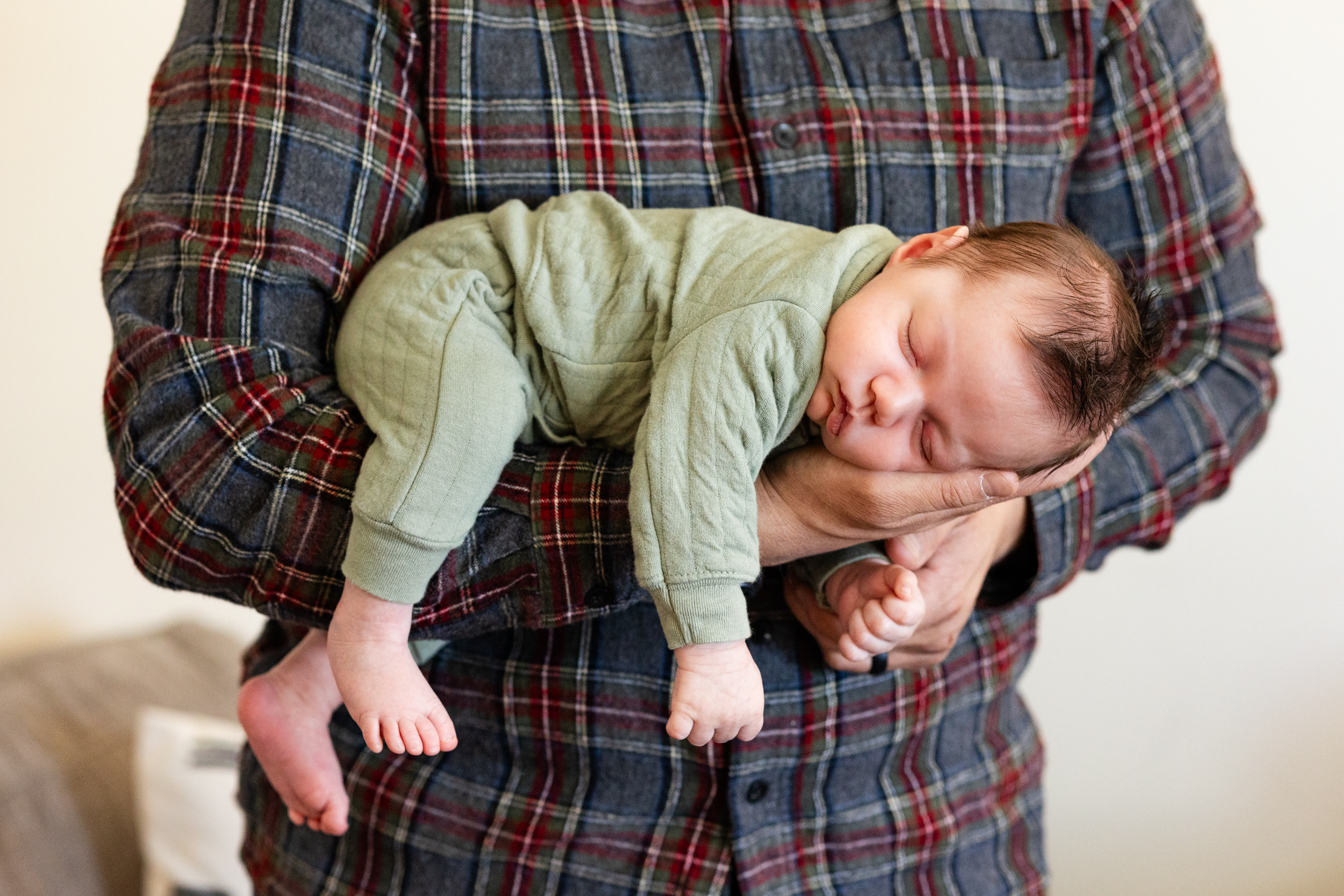 Newborn sleeps in his dad's arms.
