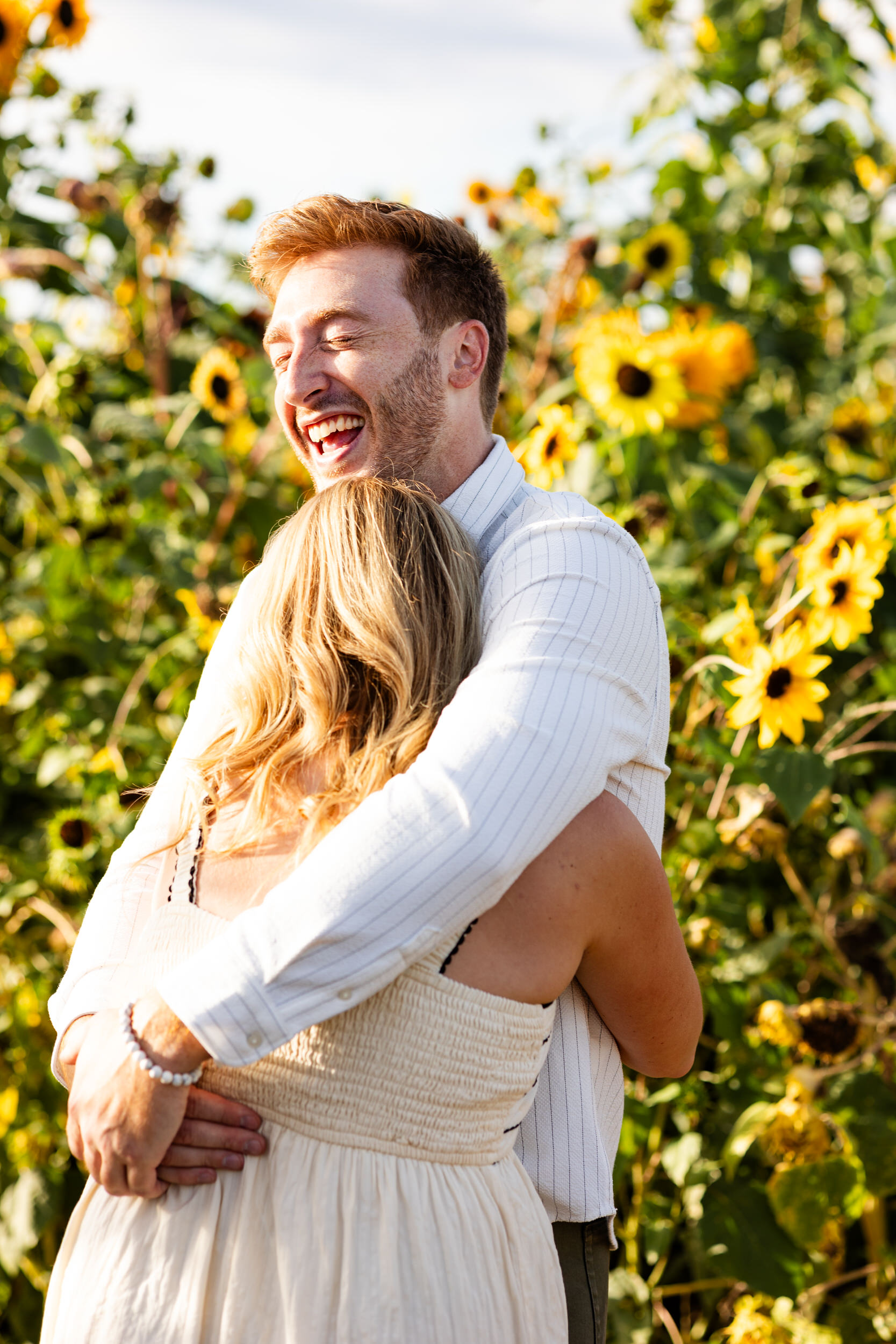 A man laughs and hugs his fiancée right after she accepts his proposal.