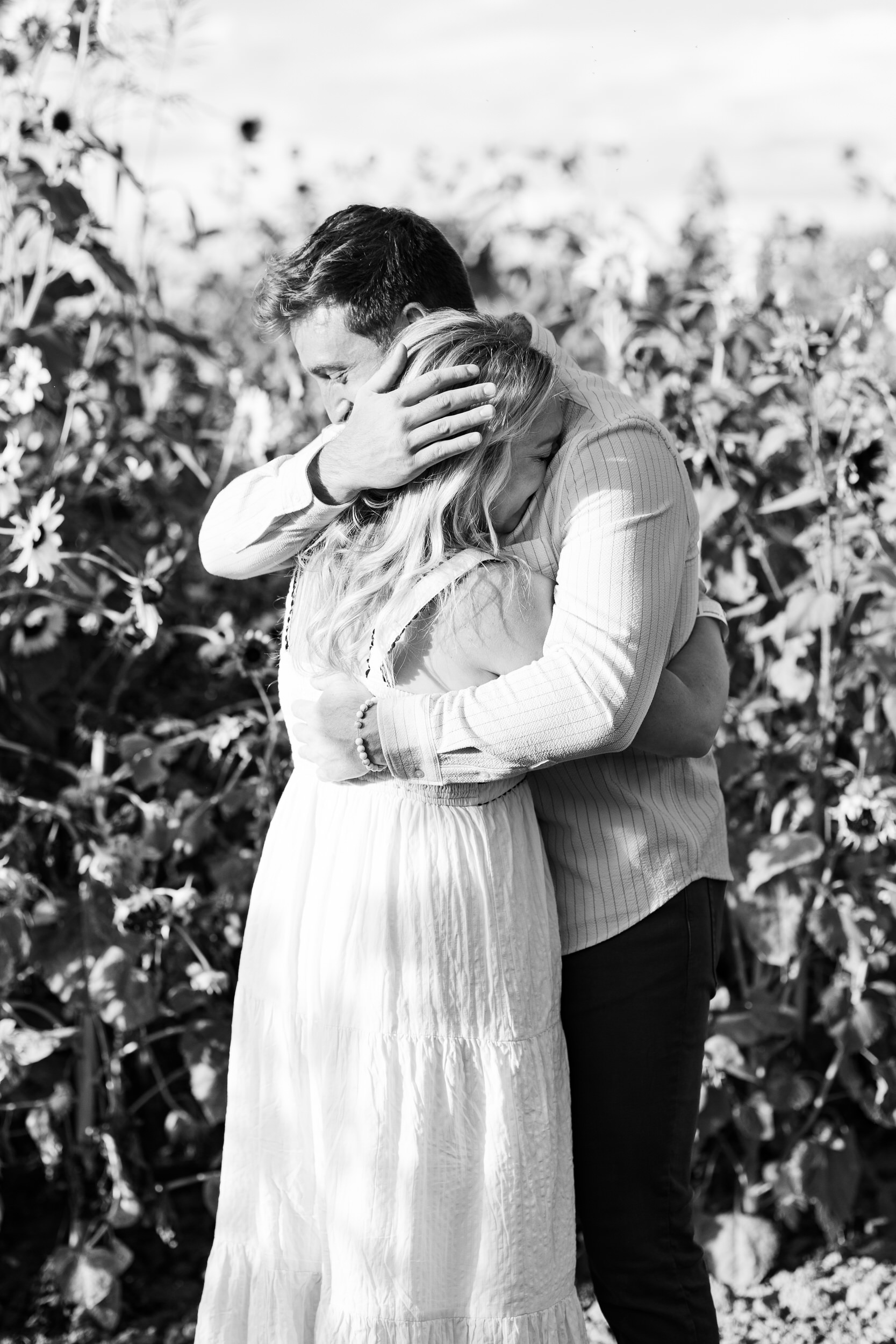 A man laughs and hugs his fiancée right after she accepts his proposal.