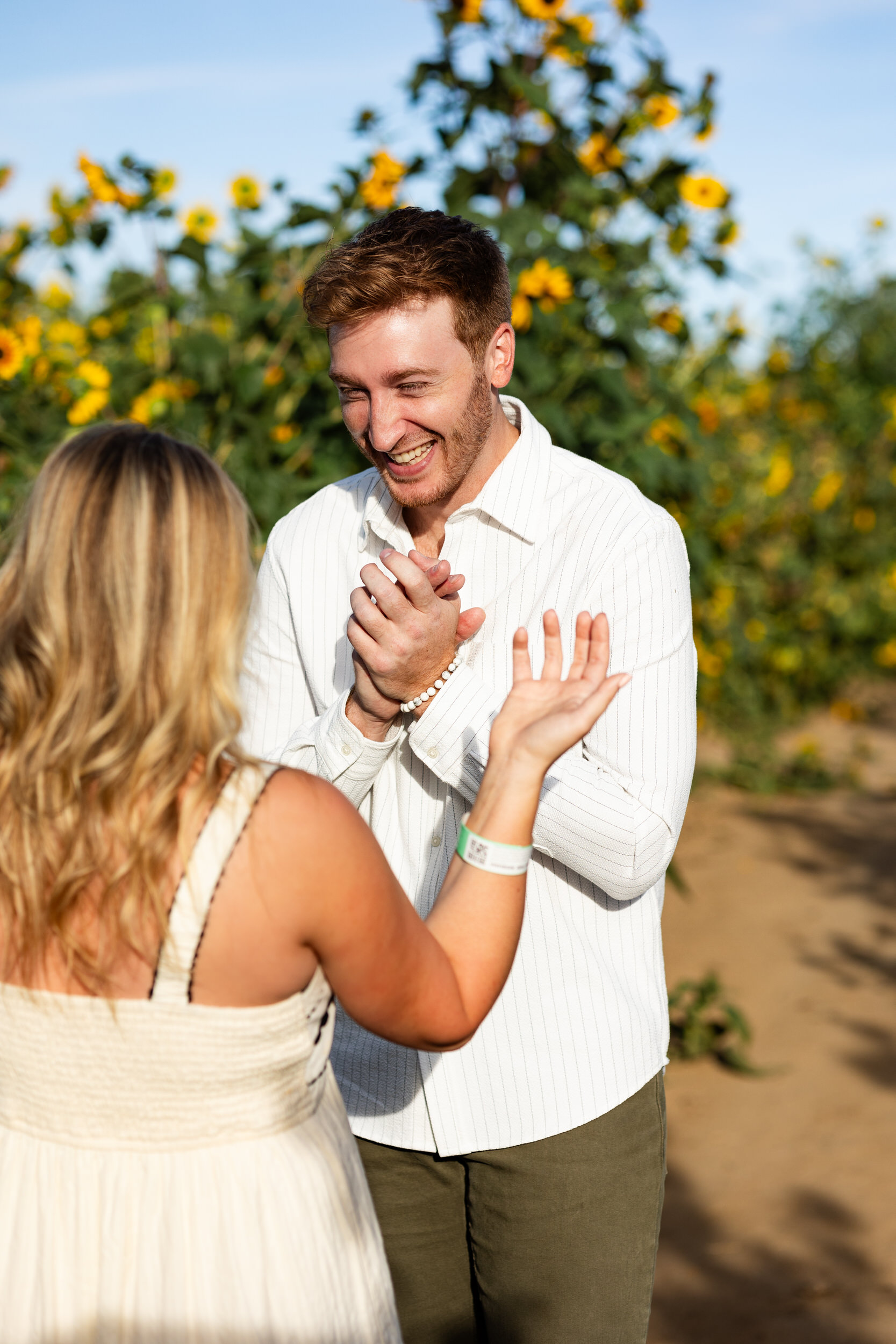 A man is smiling and looking at his fiancée right after she accepts his proposal.