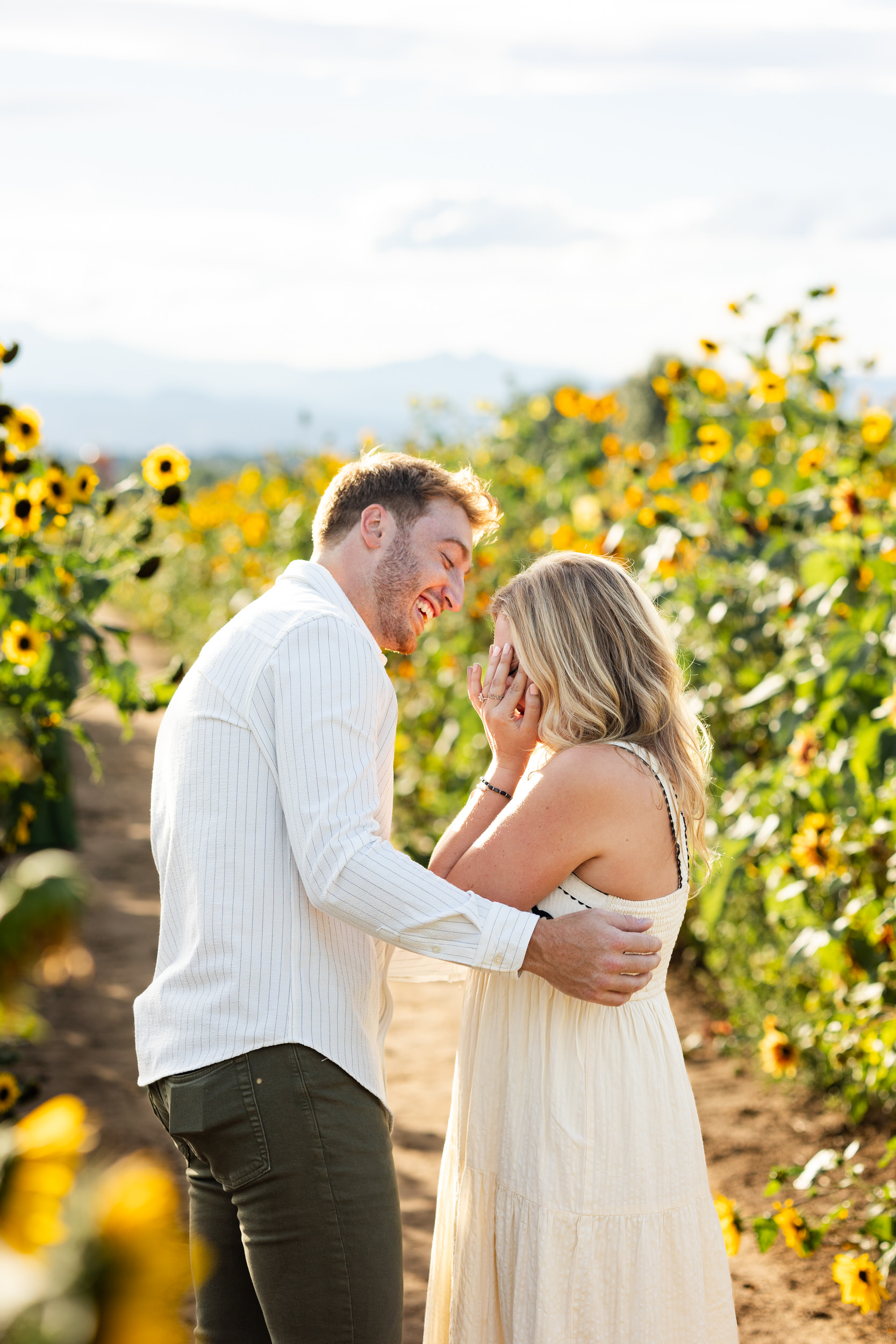 A woman is crying and her fiancé is smiling right after the proposal.