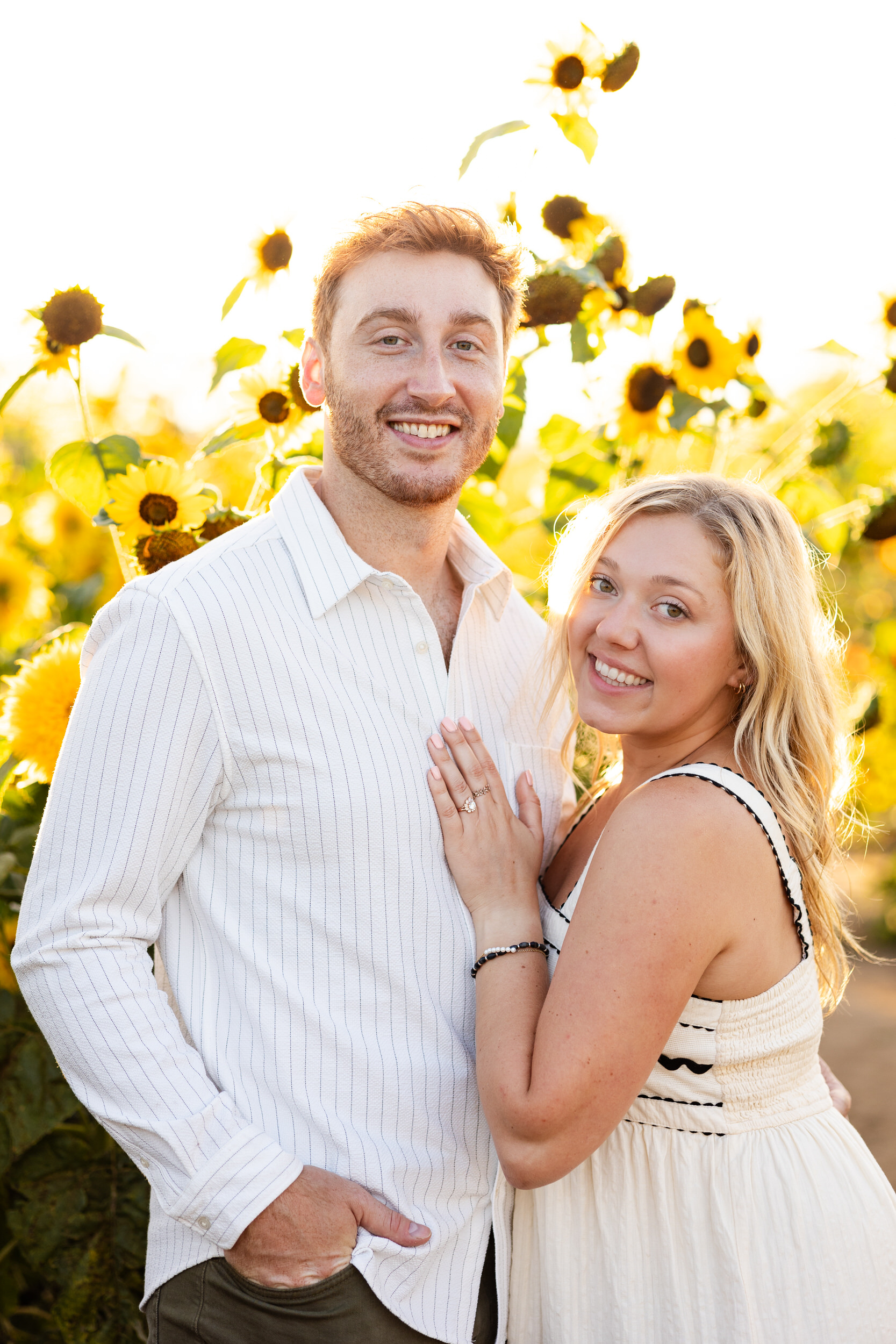 An engaged couple snuggles close and smiles at the camera.