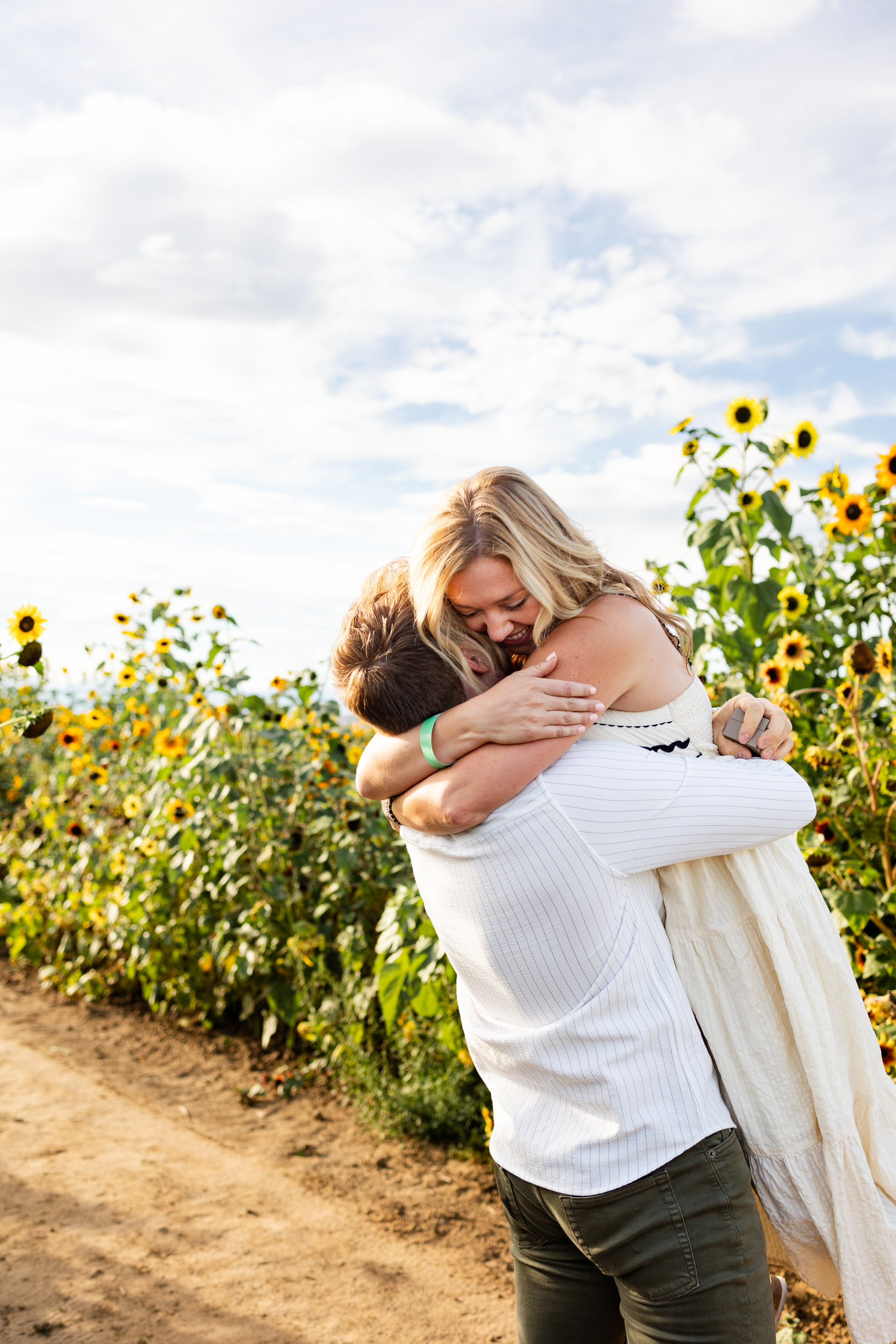 A man lifts his fiancée in a hug right after she accepts his proposal.