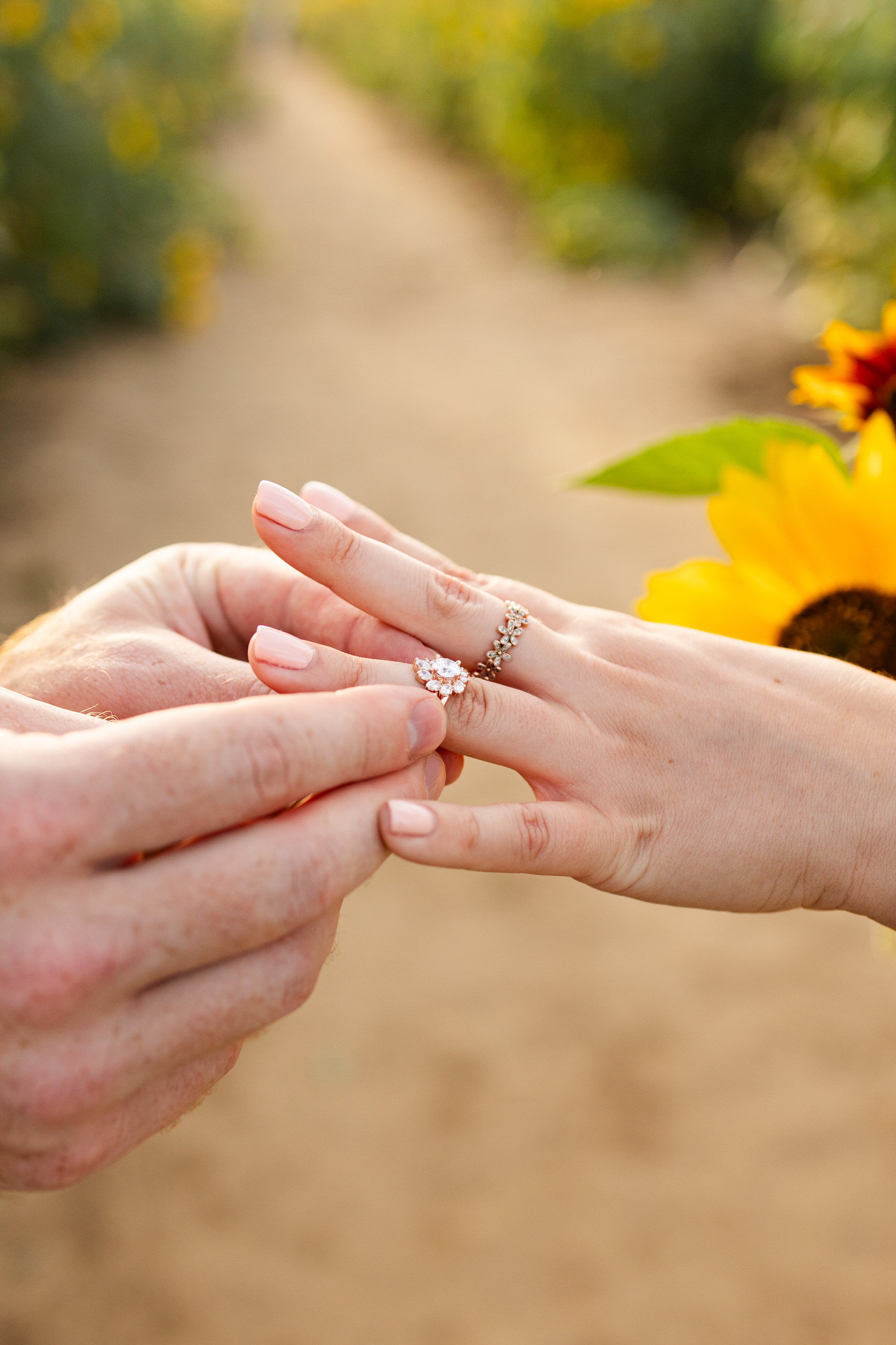 A man is sliding an engagement ring on his fiancée's finger.