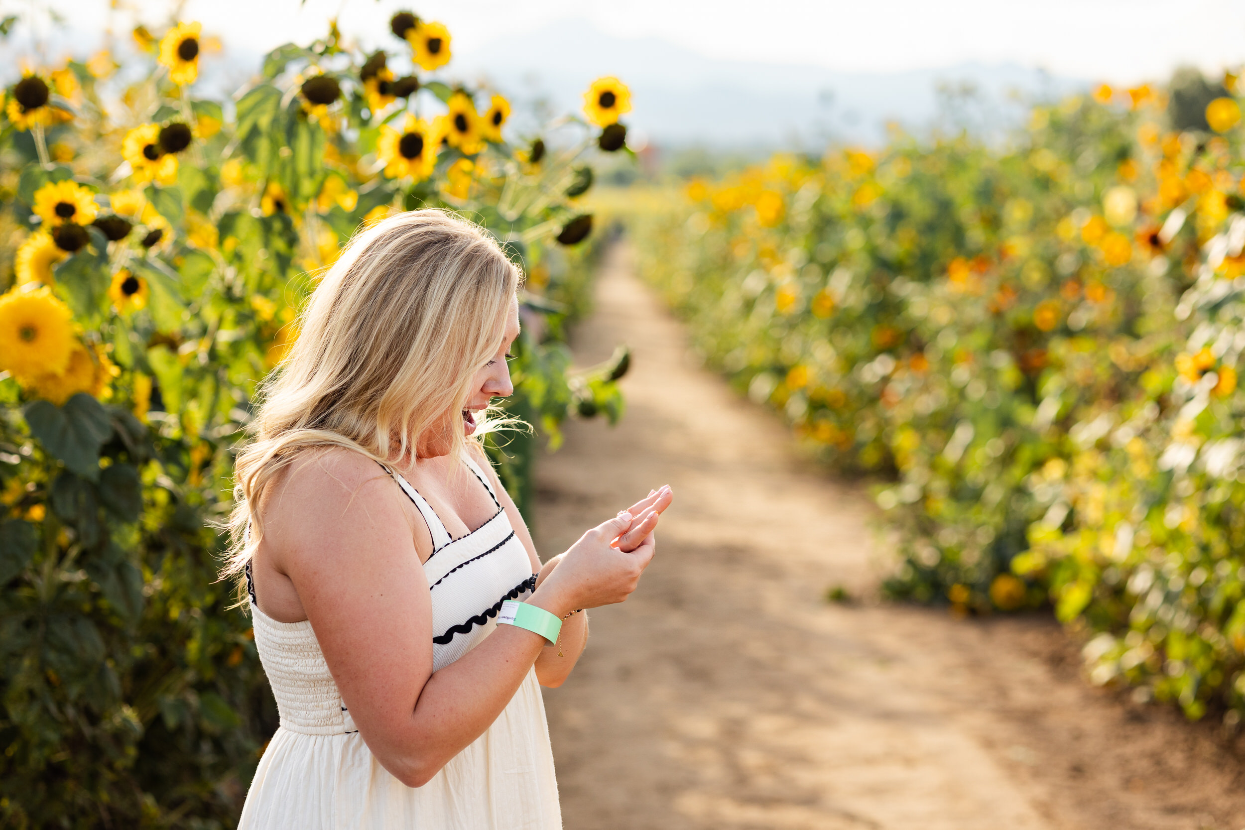 A woman looks at her new engagement ring with a big smile.