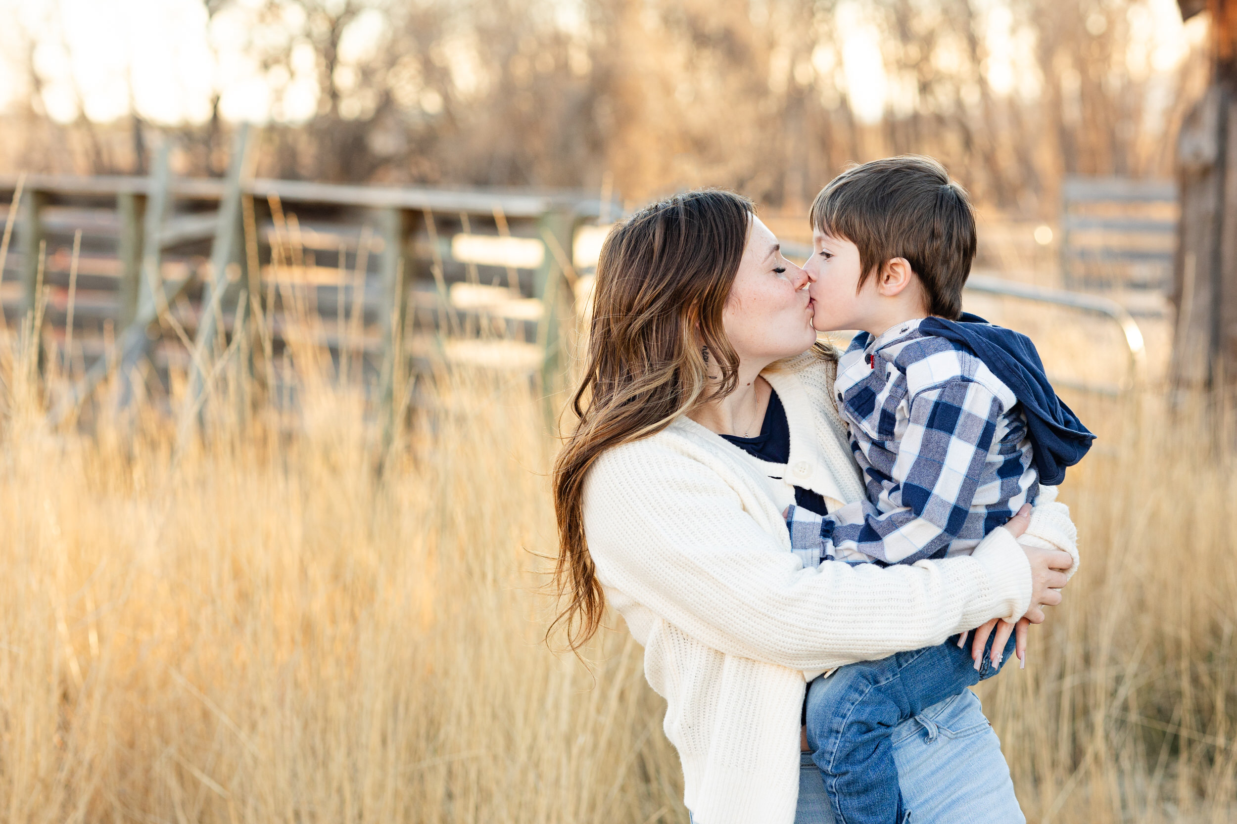 A mom holds her young son and they share a sweet kiss.