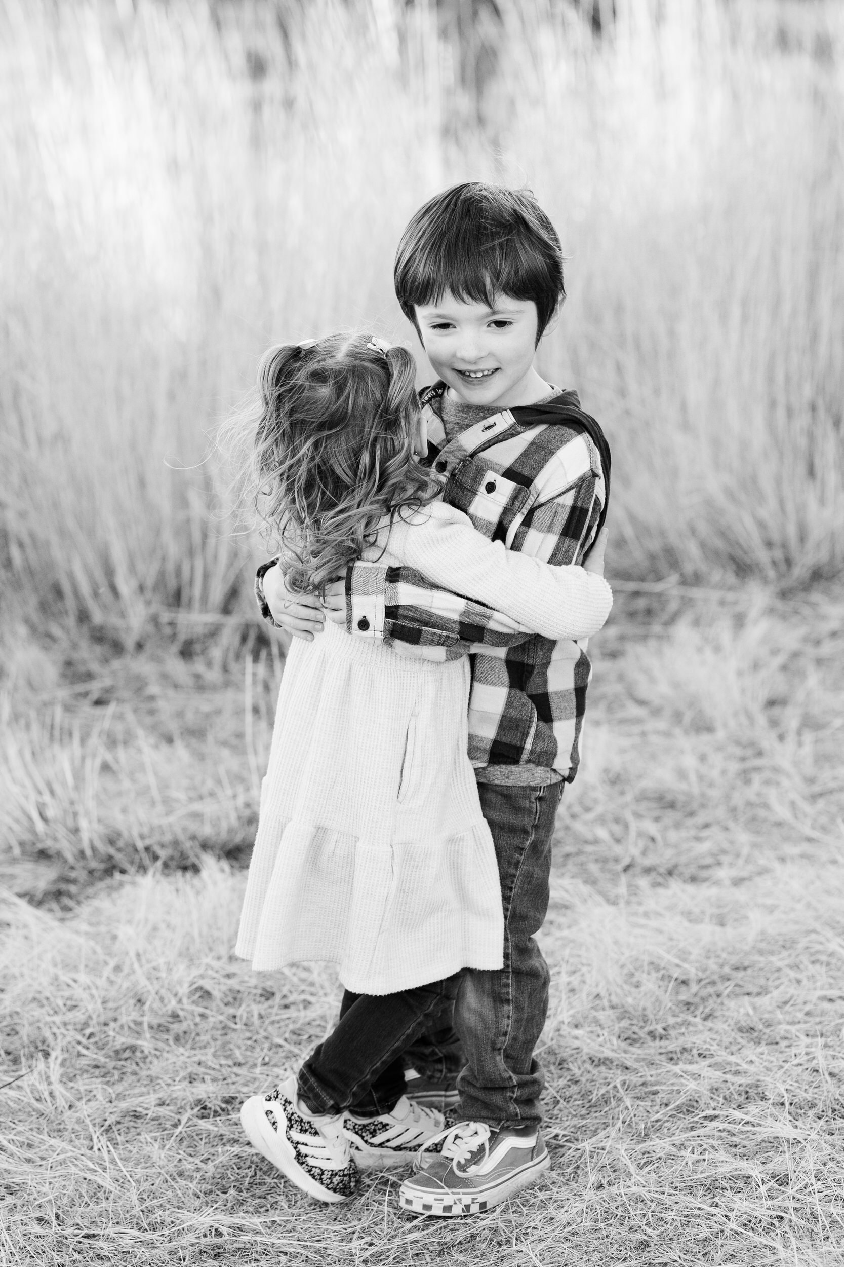 A young brother and sister hug each other.