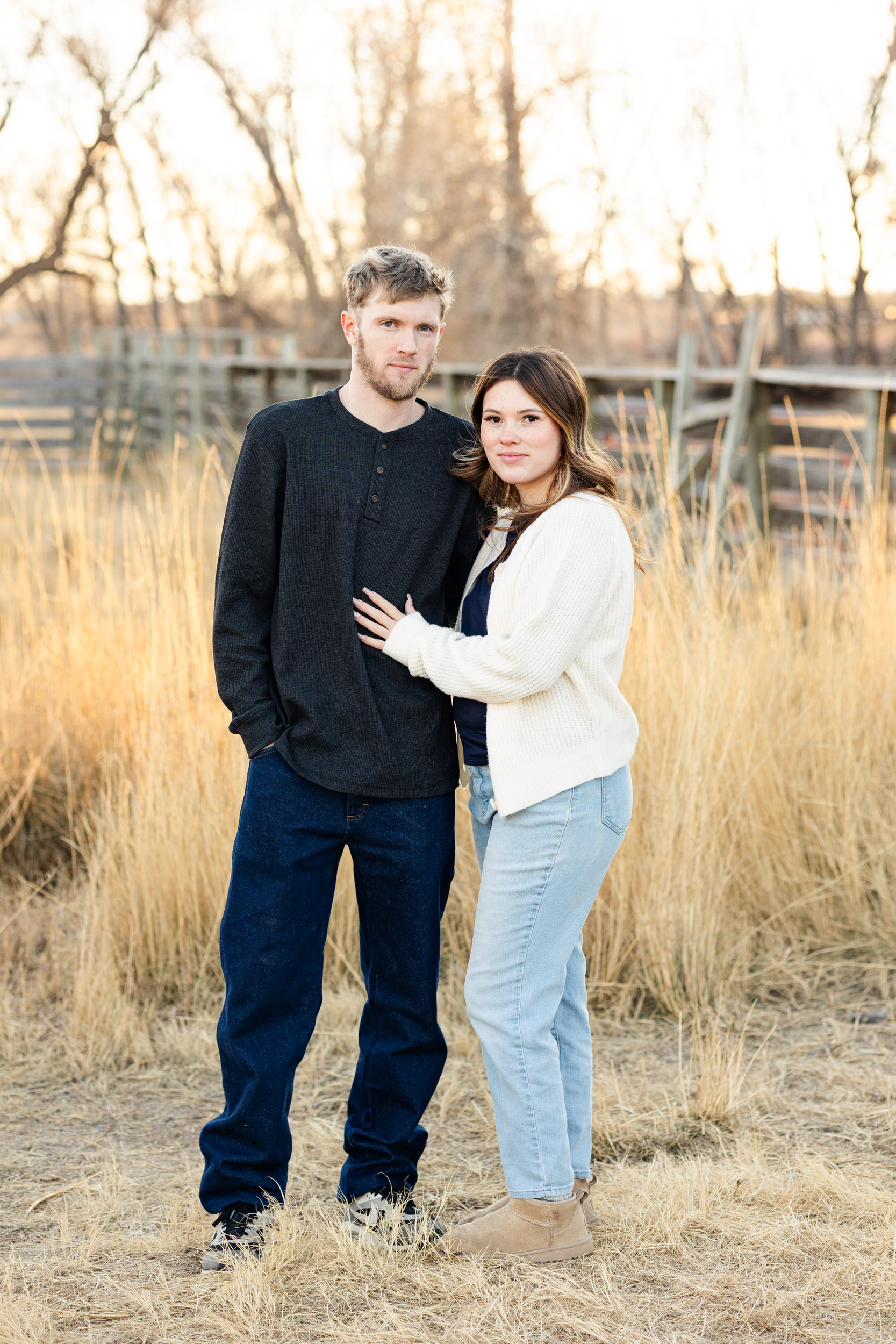 A couple stands close to each other and they smile at the camera.