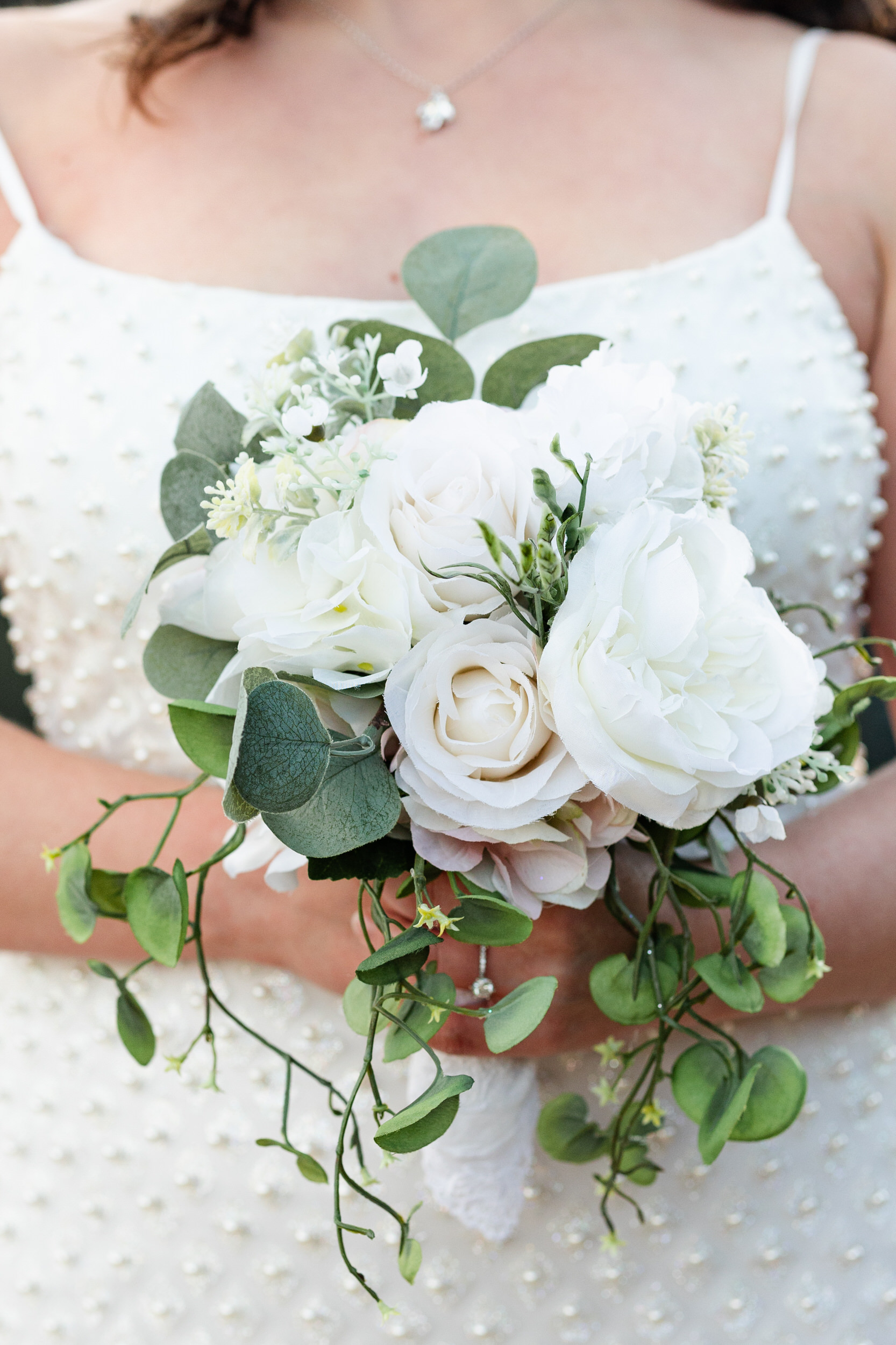 A woman in a white dress holds a bouquet of flowers.