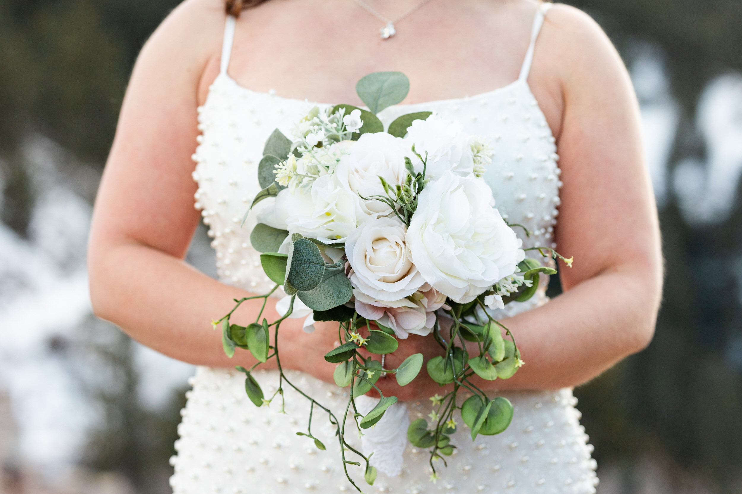 Close-up of a woman holding a bouquet of white flowers.