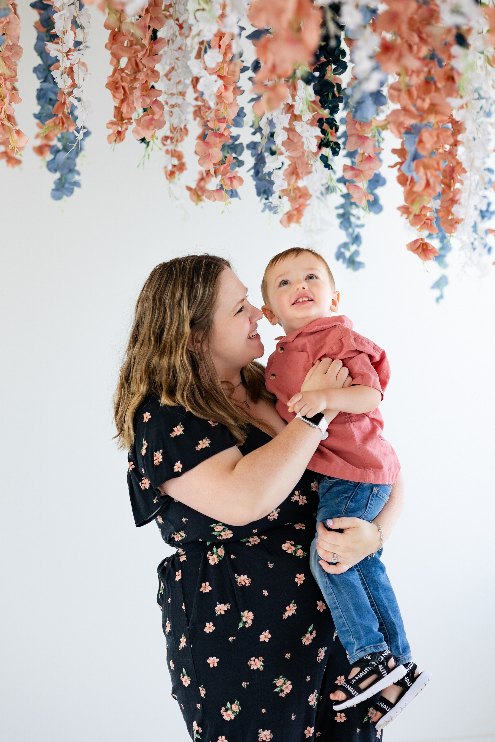 A mom holds her toddler son and smiles at him.