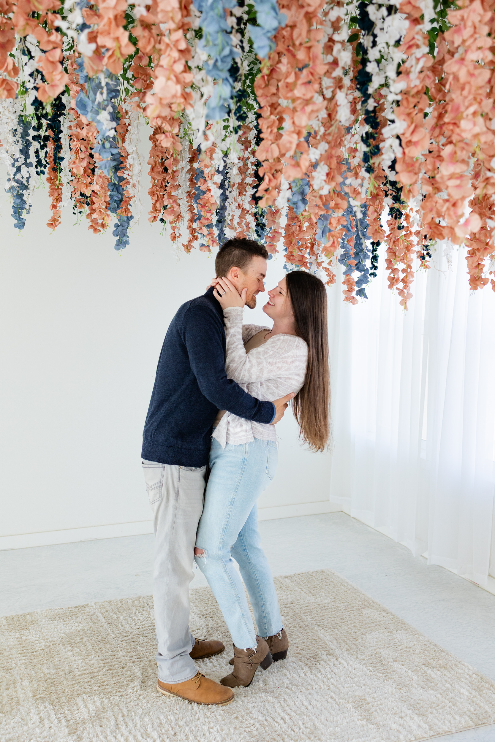 A husband and wife hold each other close and care caught on camera smiling as they lean in for a kiss.