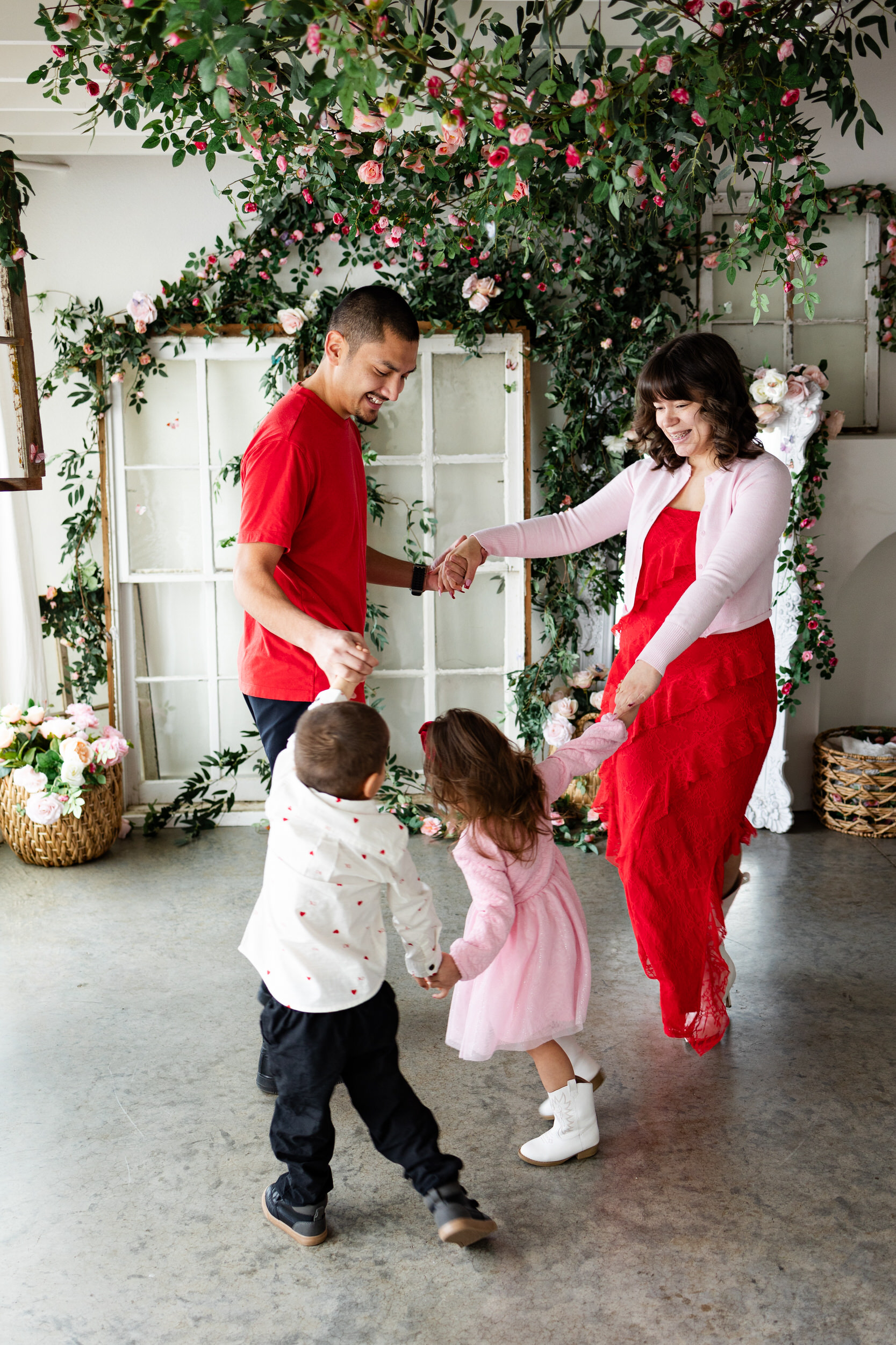 A mom and dad play Ring Around the Rosie with their two young kids.