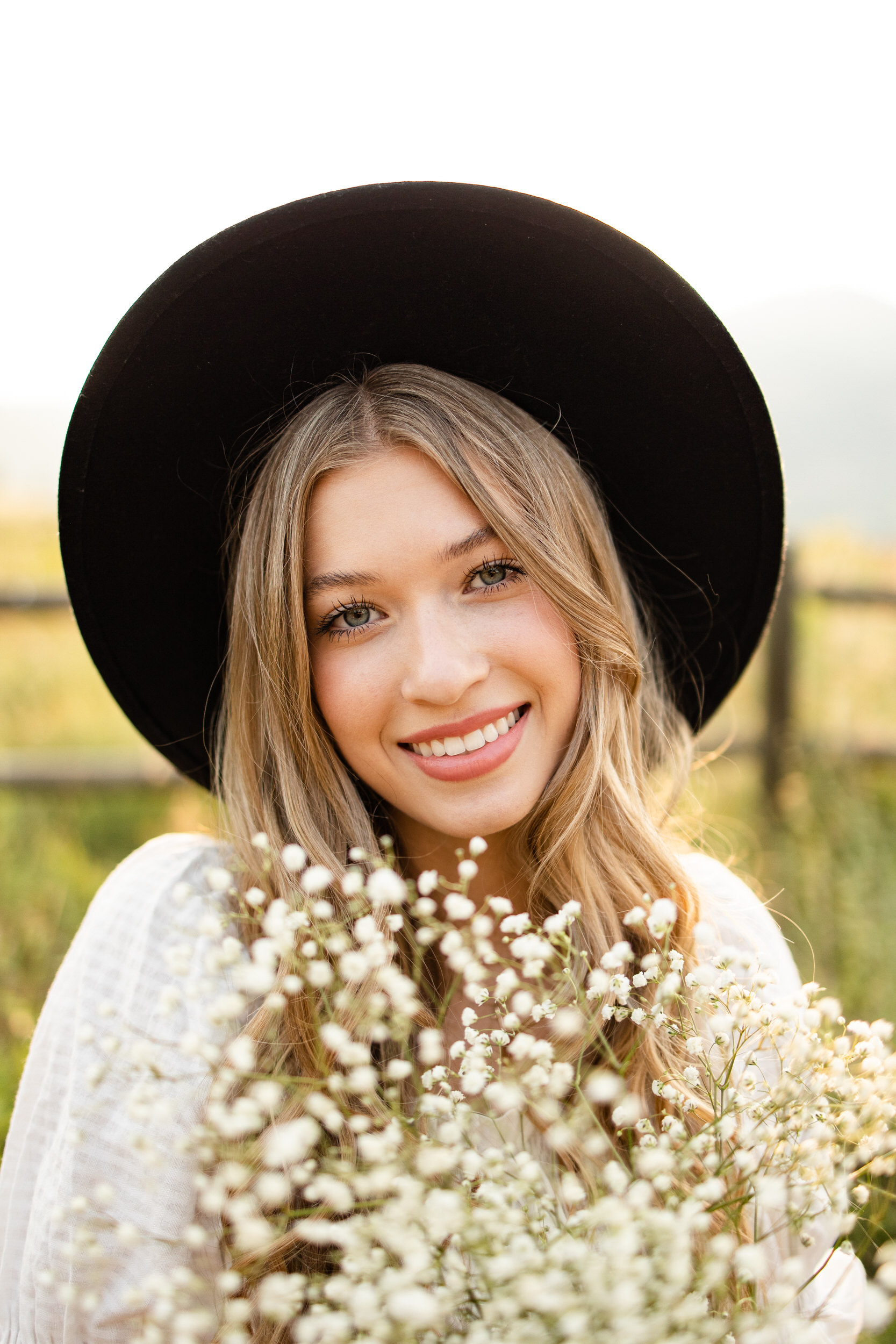 Woman in a black hat holding white flowers