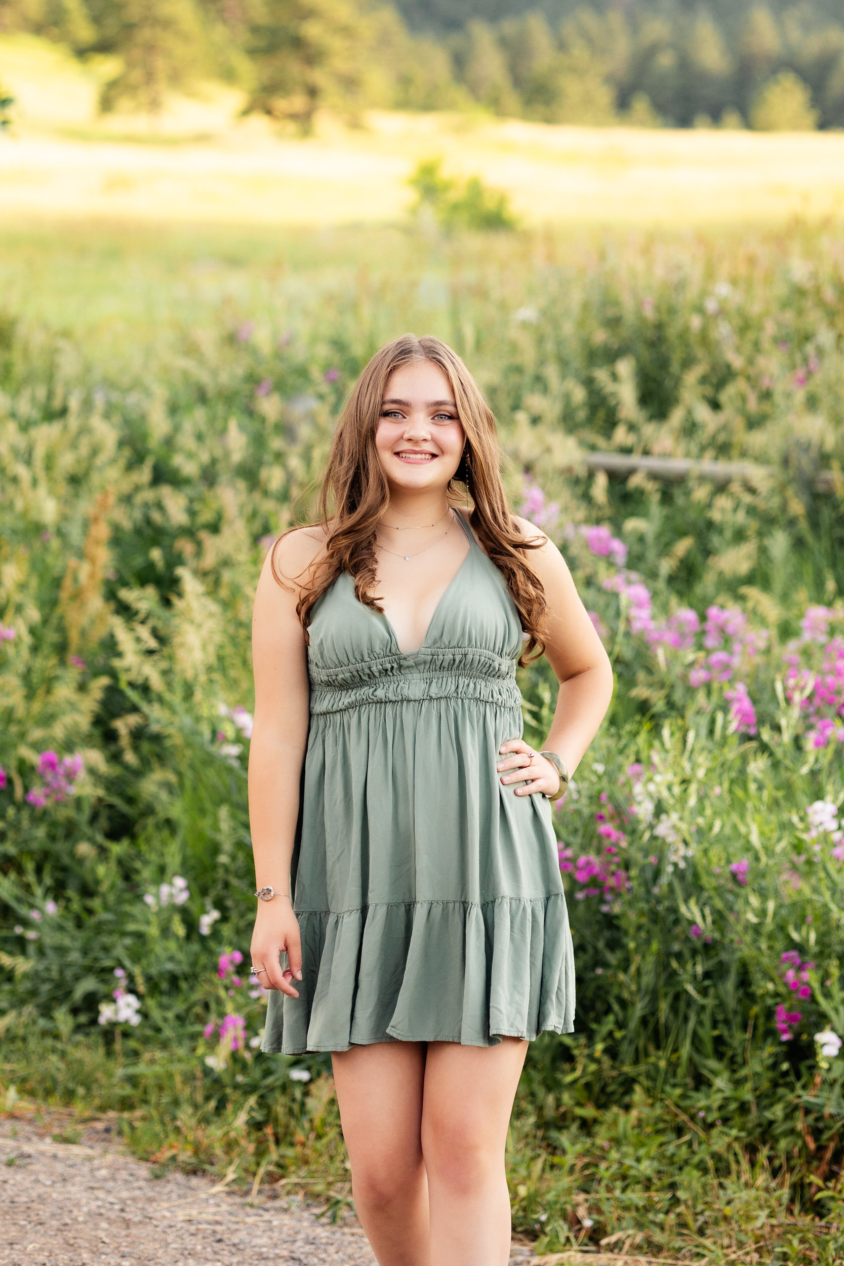 A woman in a green dress surrounded by wildflowers walks toward the camera.