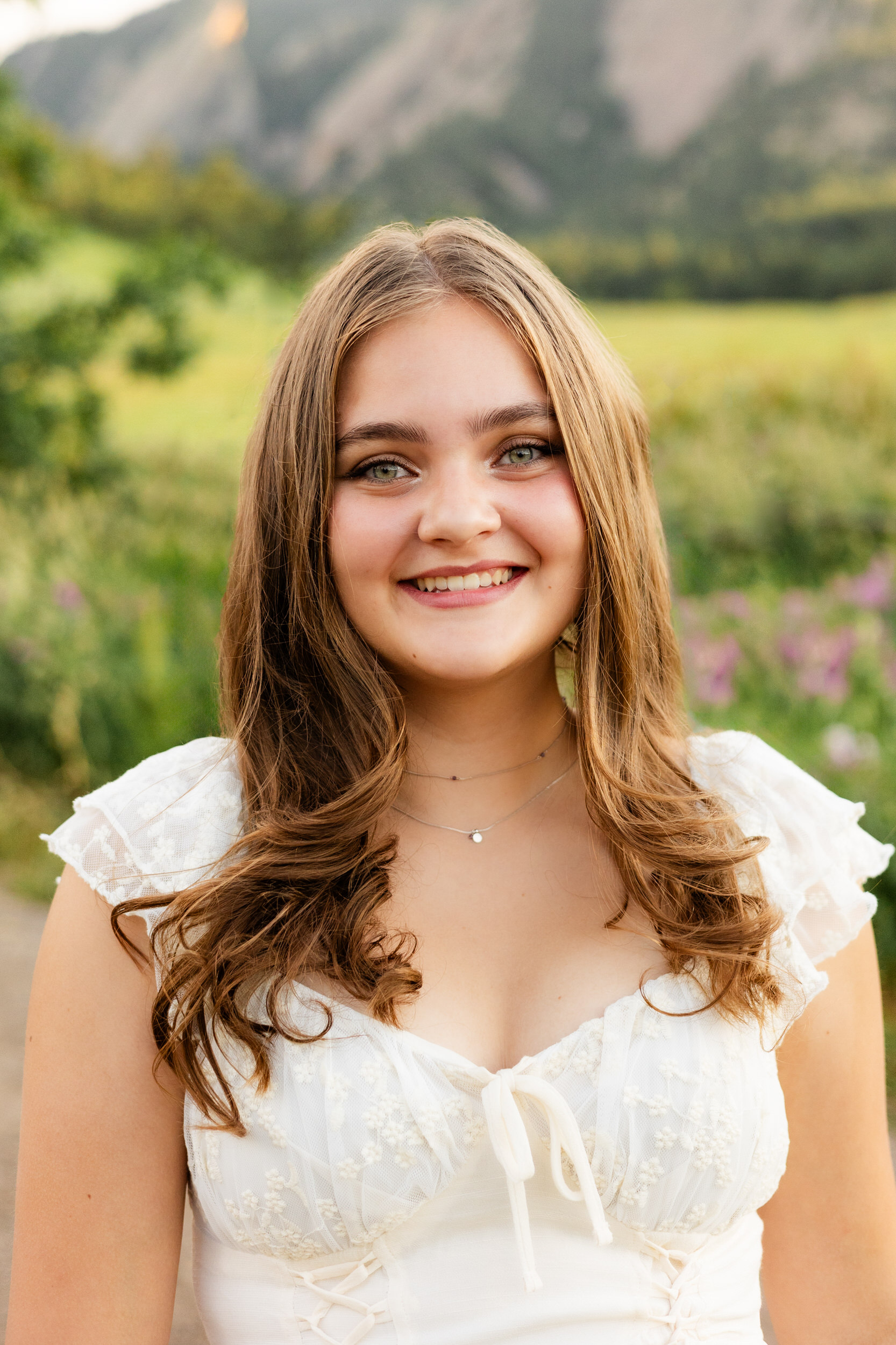 A woman in a white dress smiles at the camera.
