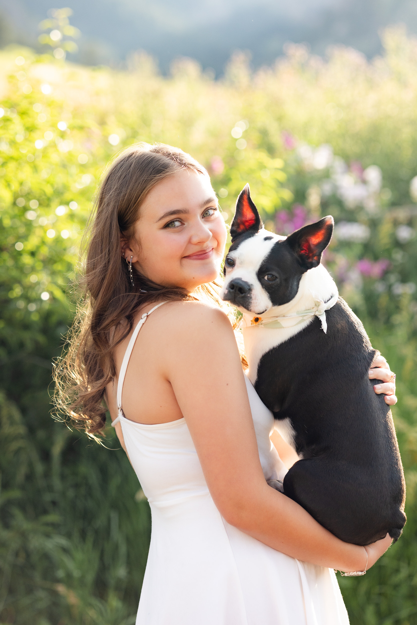 A woman holds her French Bulldog and smiles at the camera.