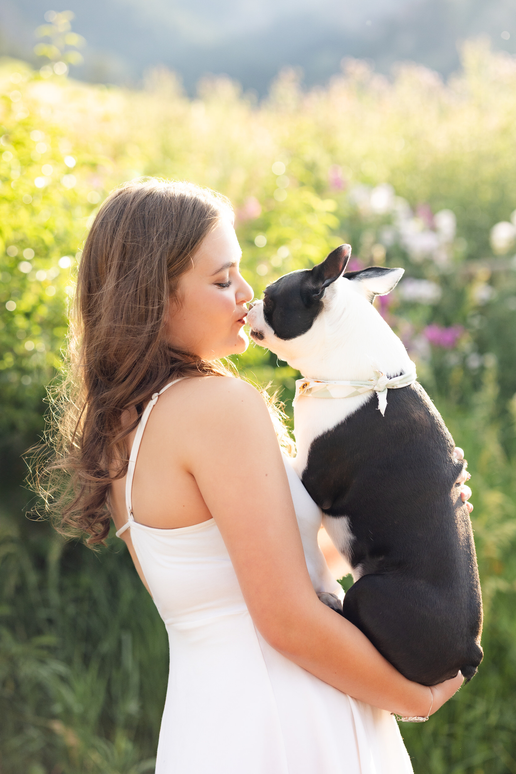 A woman kisses her French Bulldog on the nose.