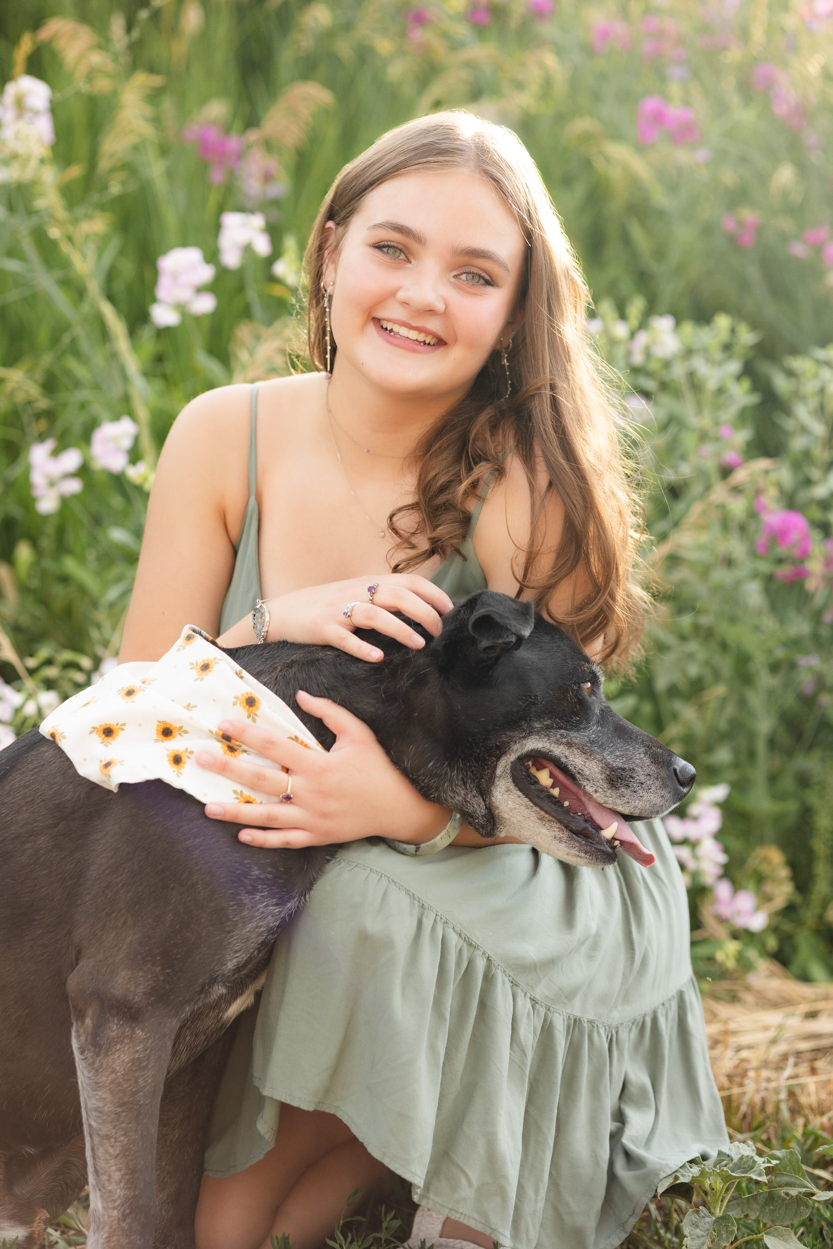 A woman hugs her dog and smiles at the camera.