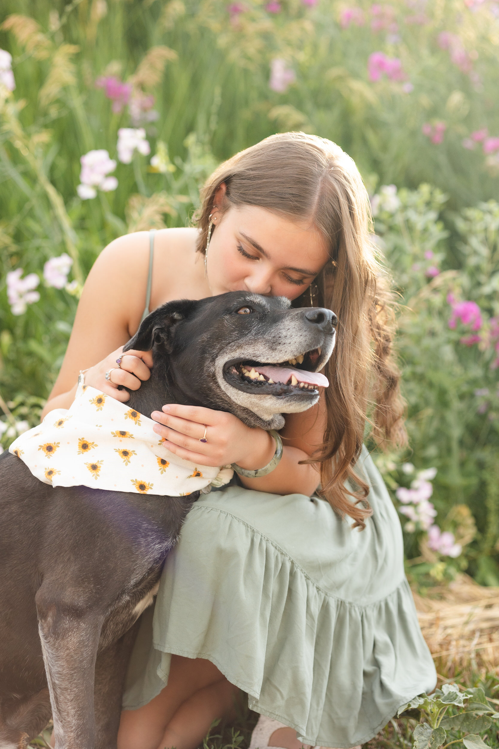 A woman kisses her dog on the head.