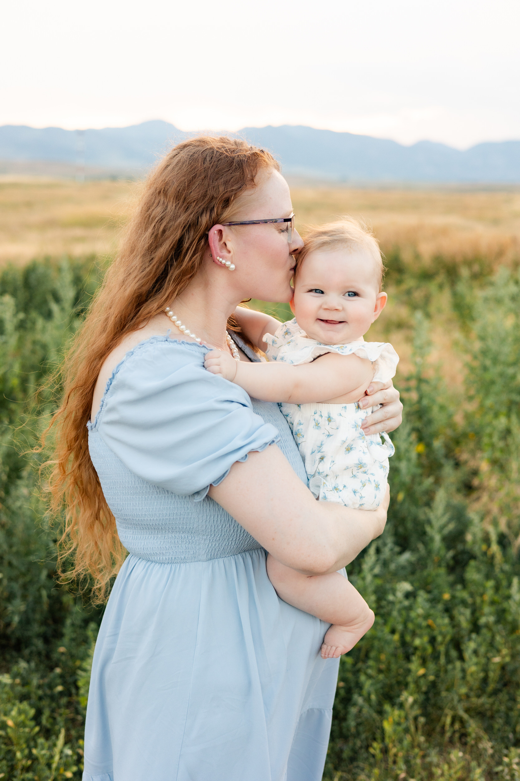 Mom holds and kisses her baby girl.