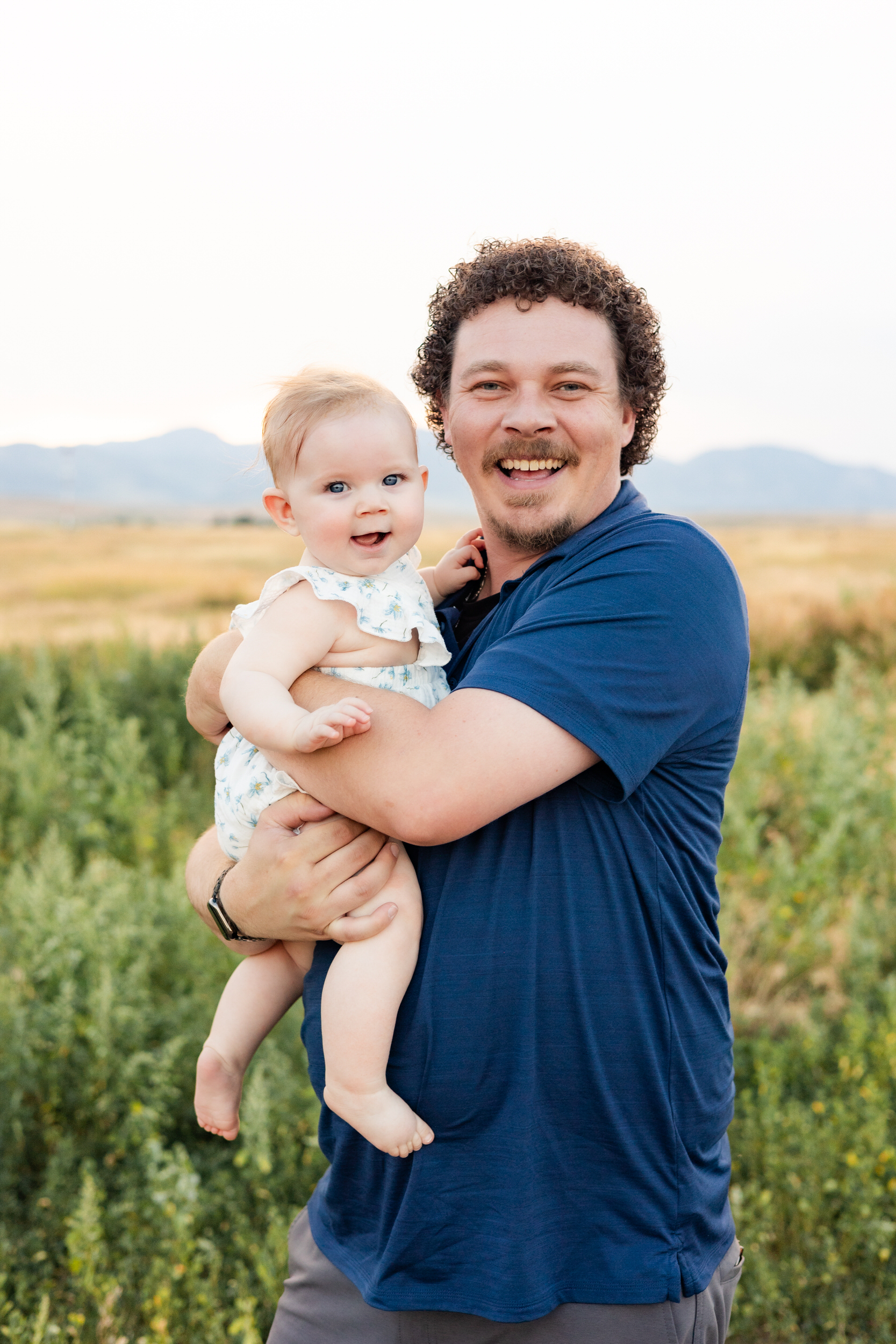 Dad and baby girl smile at the camera.