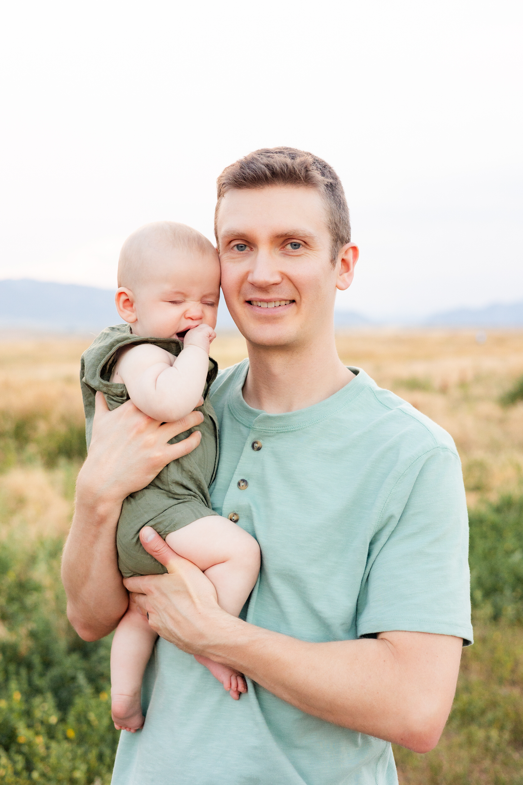 Dad holds yawning baby boy.
