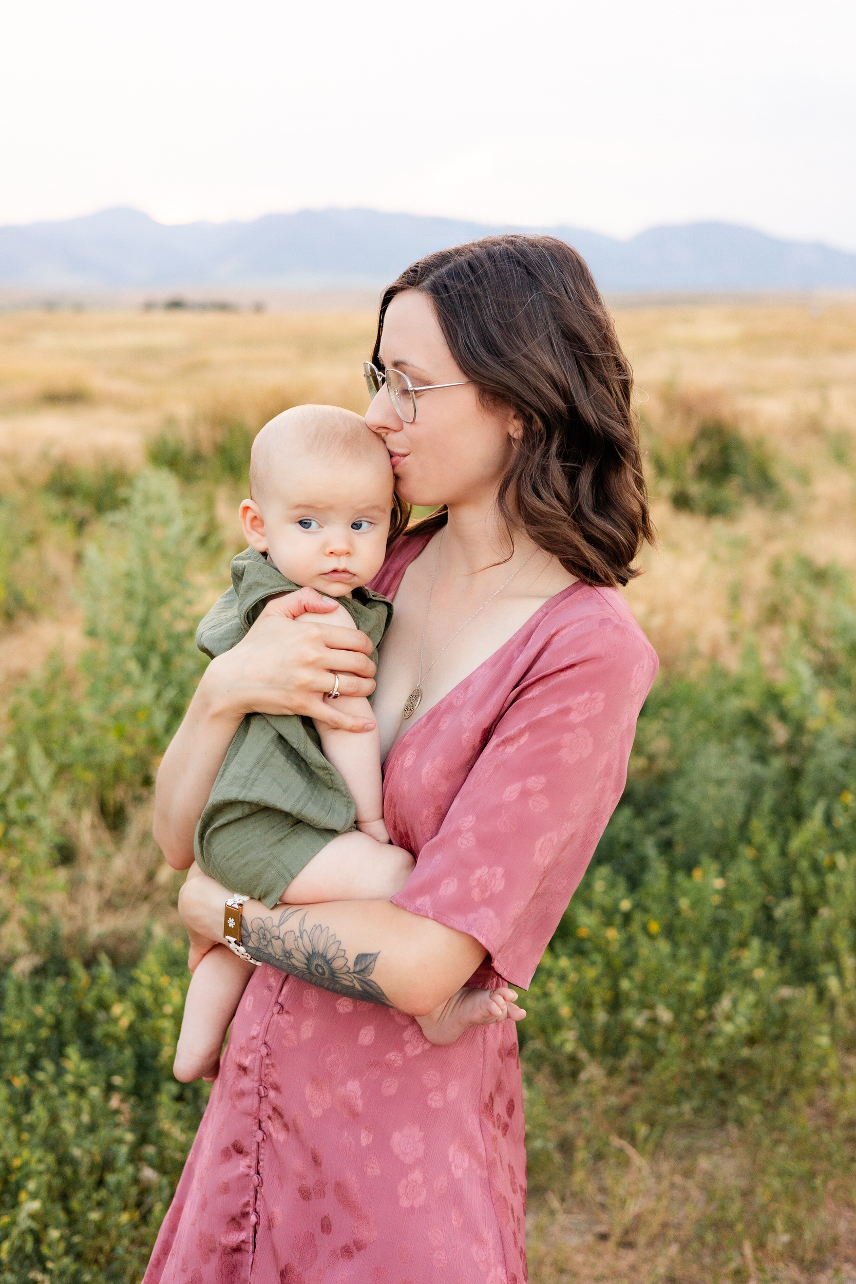 Mom kisses baby boy on his head.