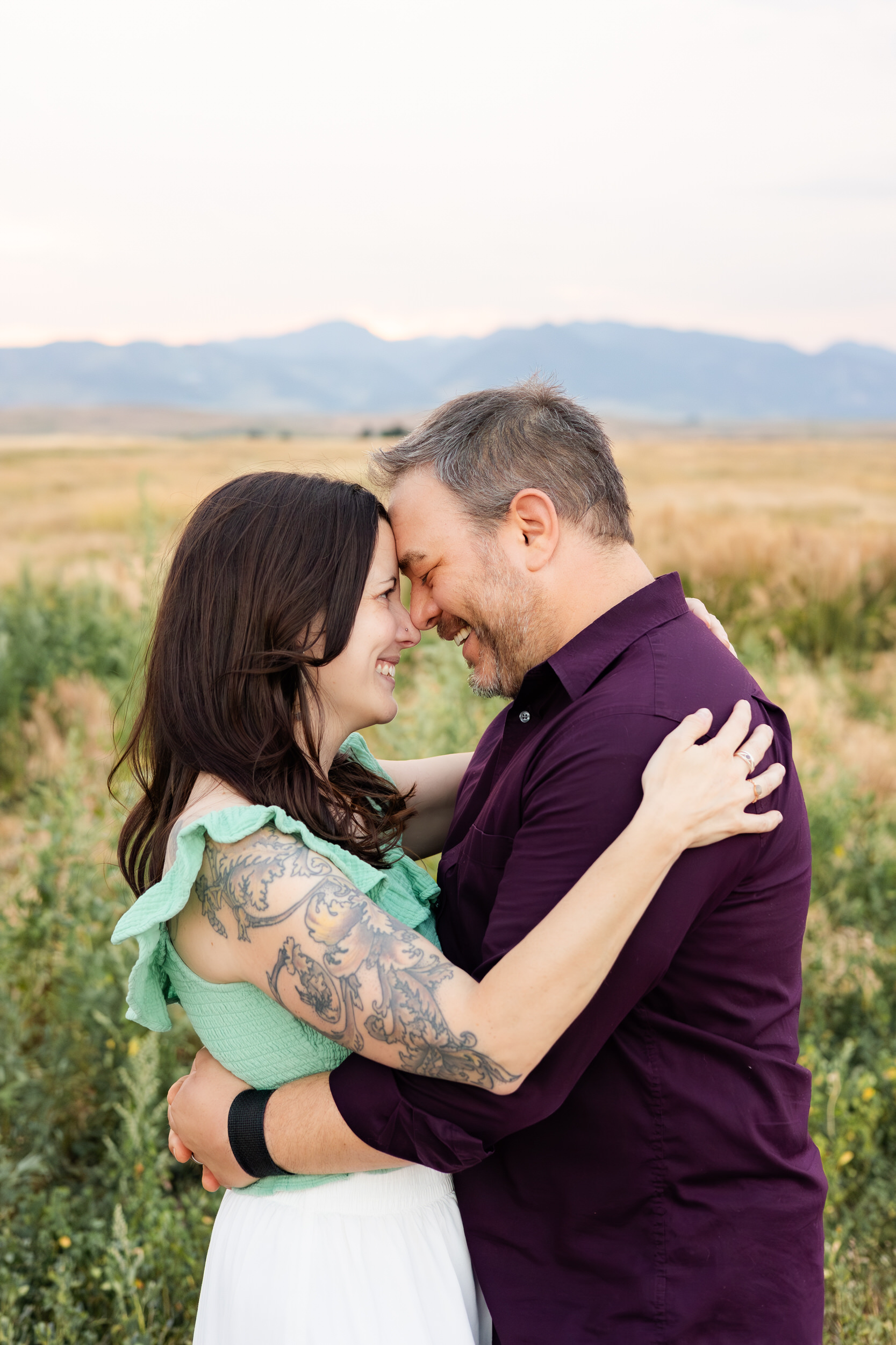 Husband and wife stand forehead to forehead.