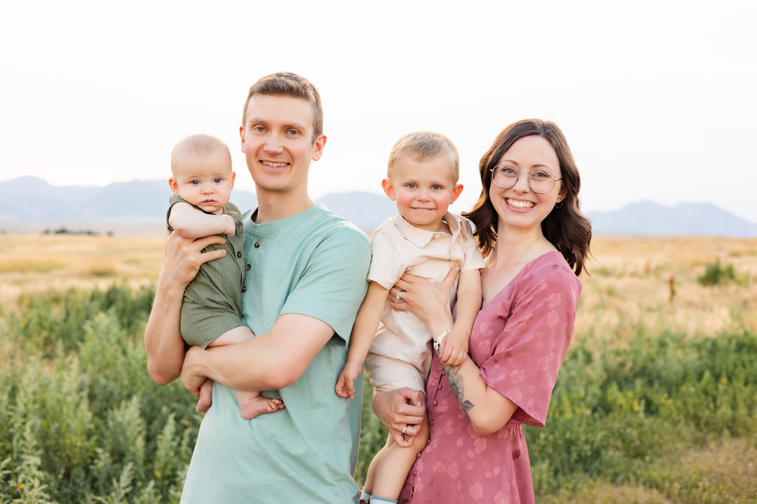 Mom, dad, baby boy, and toddler son smile at the camera.