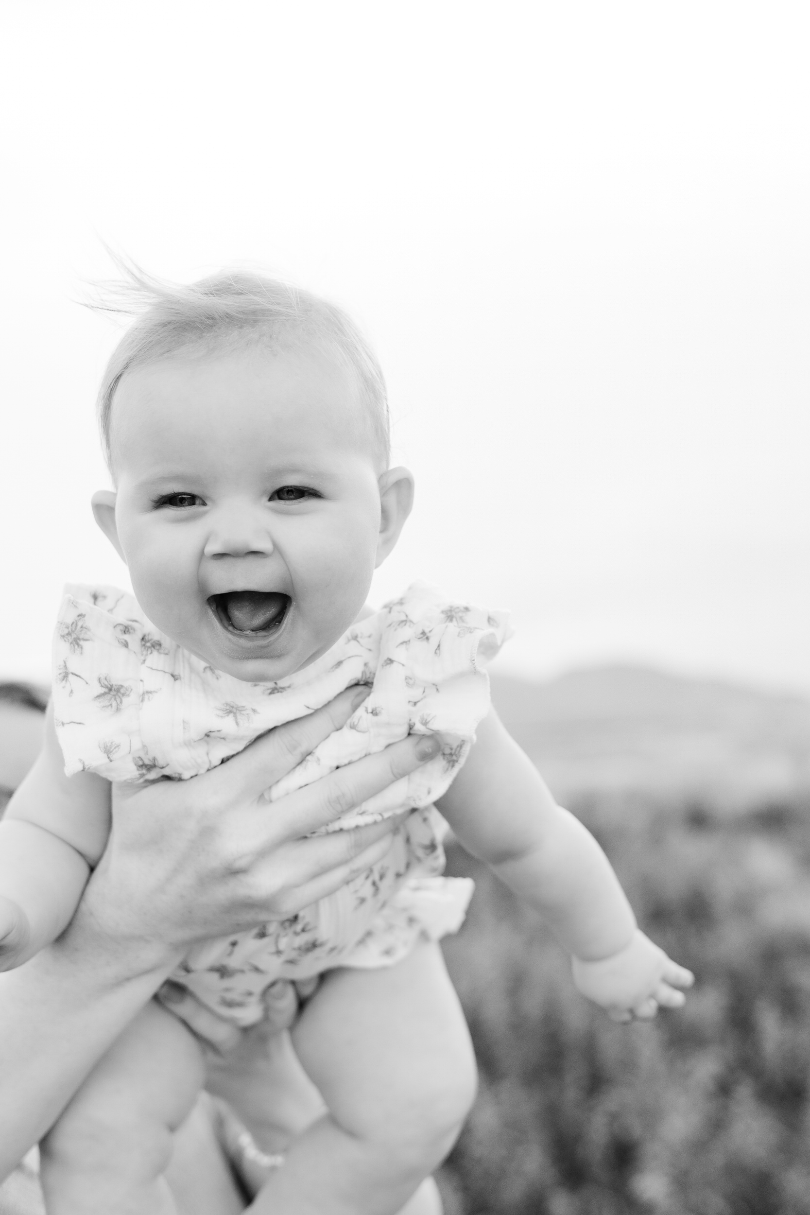 Baby girl laughs while mom holds her.