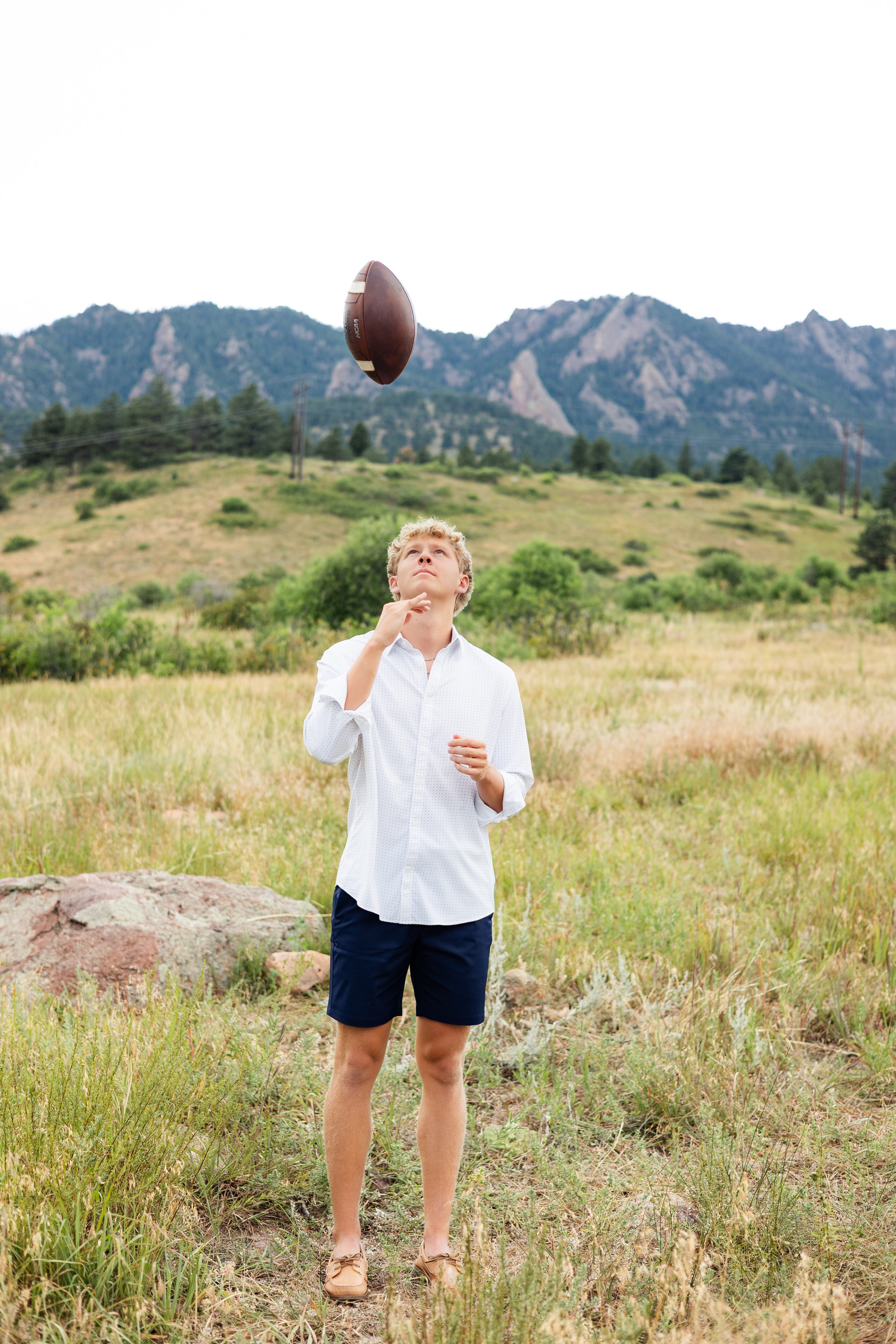 A young man tosses a football into the air.