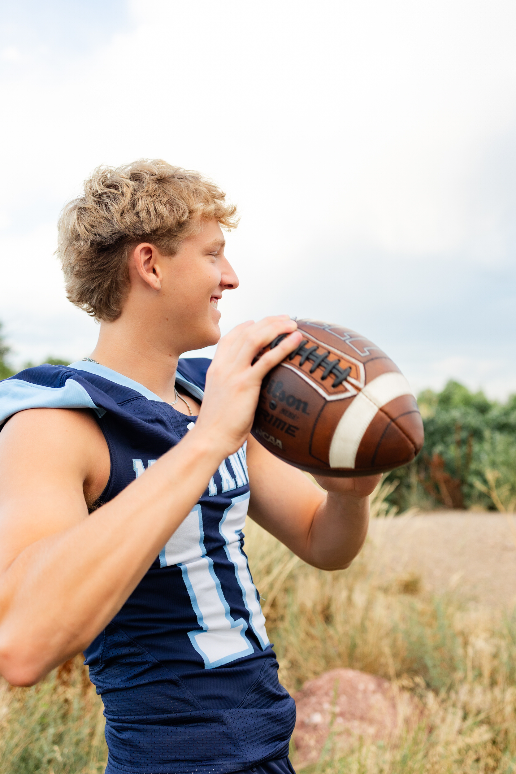 A young man in a school football jersey throws a football.